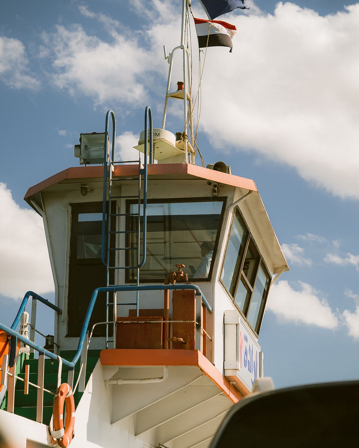 The cockpit of a vessel is highlighted against the blue sky with clouds.