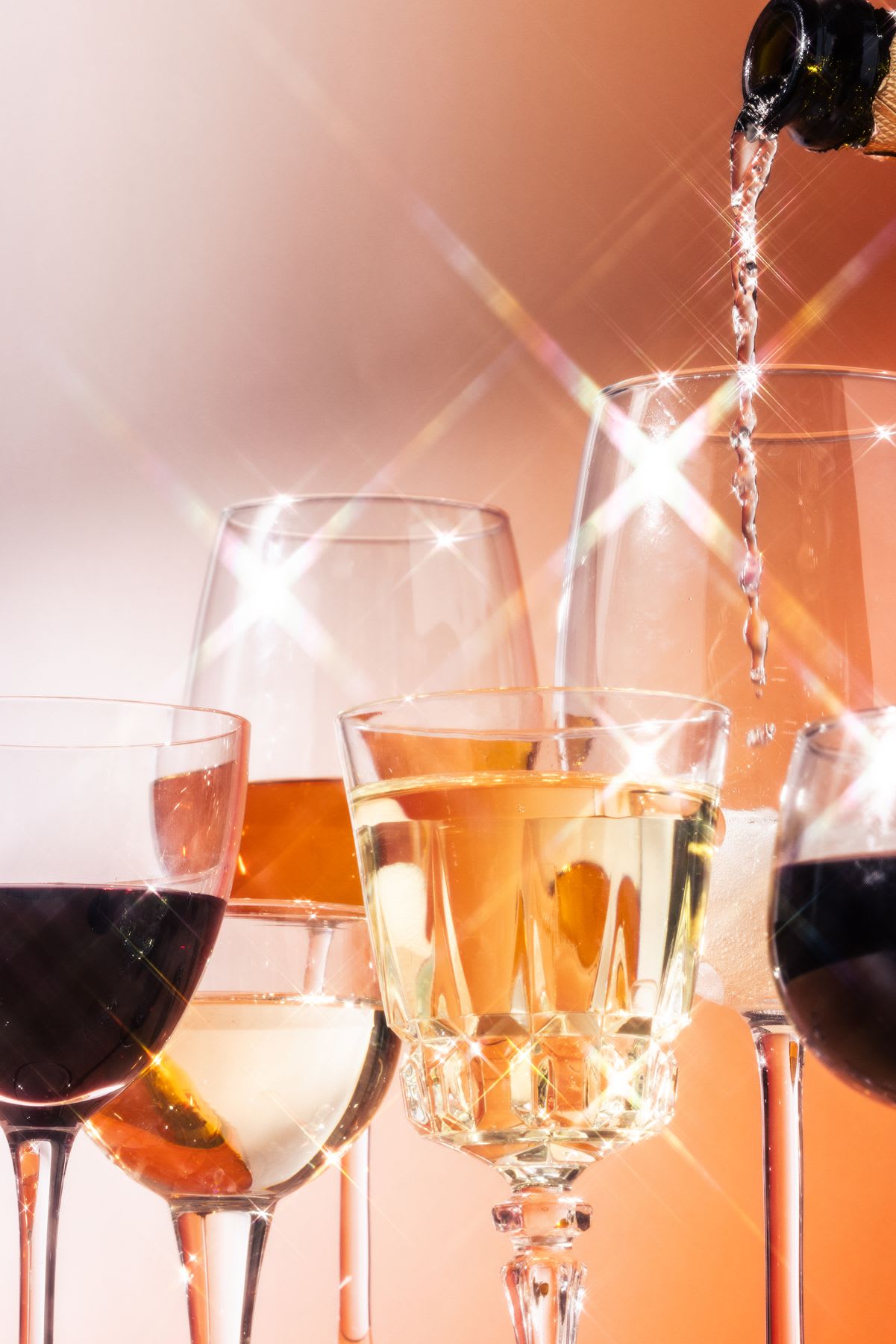 Several glasses of different sizes with liquids and they are shiny