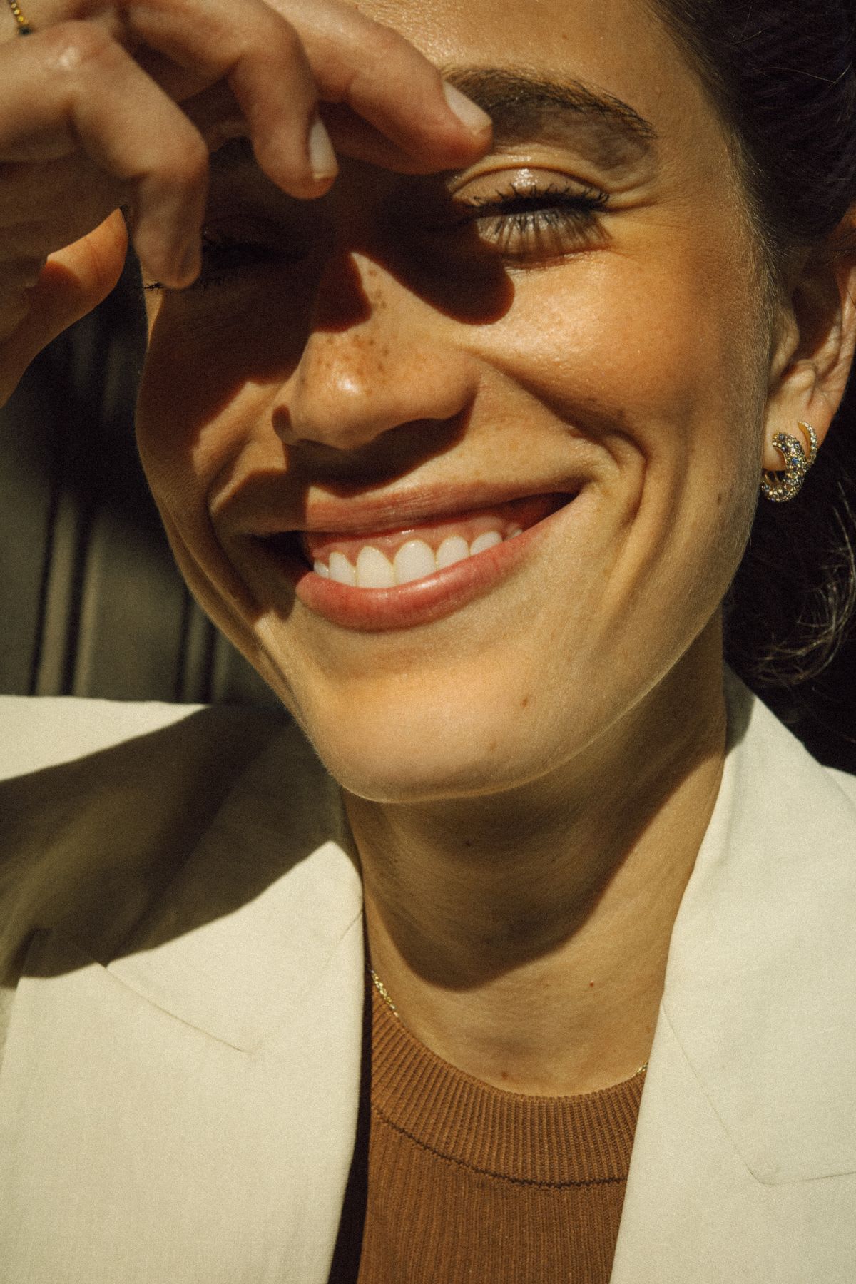 Portrait of a smiling woman with her right hand against her forehead.