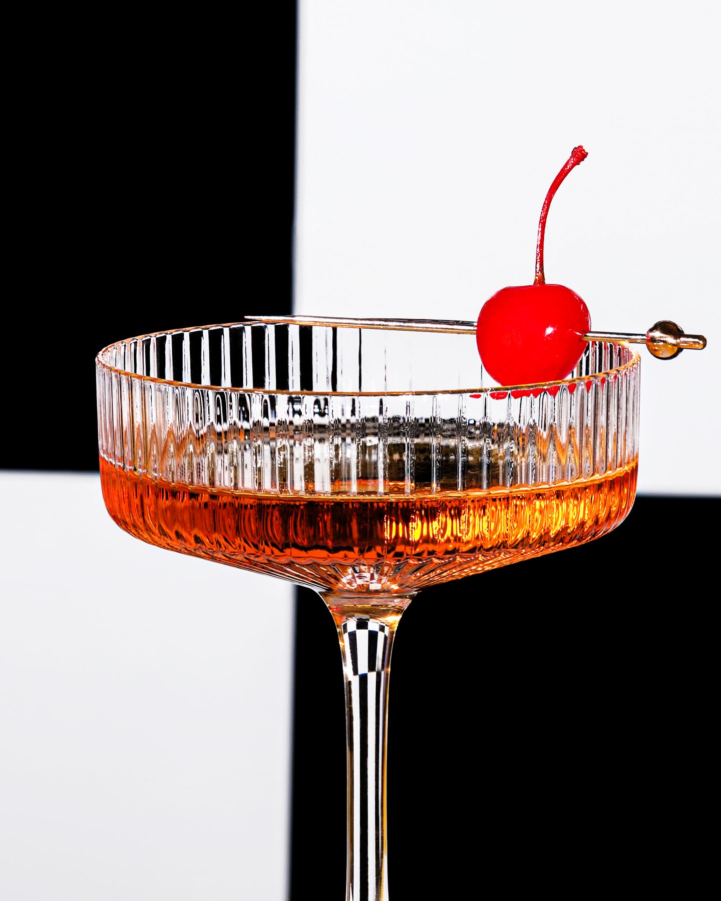 A cocktail garnished with a candied cherry.