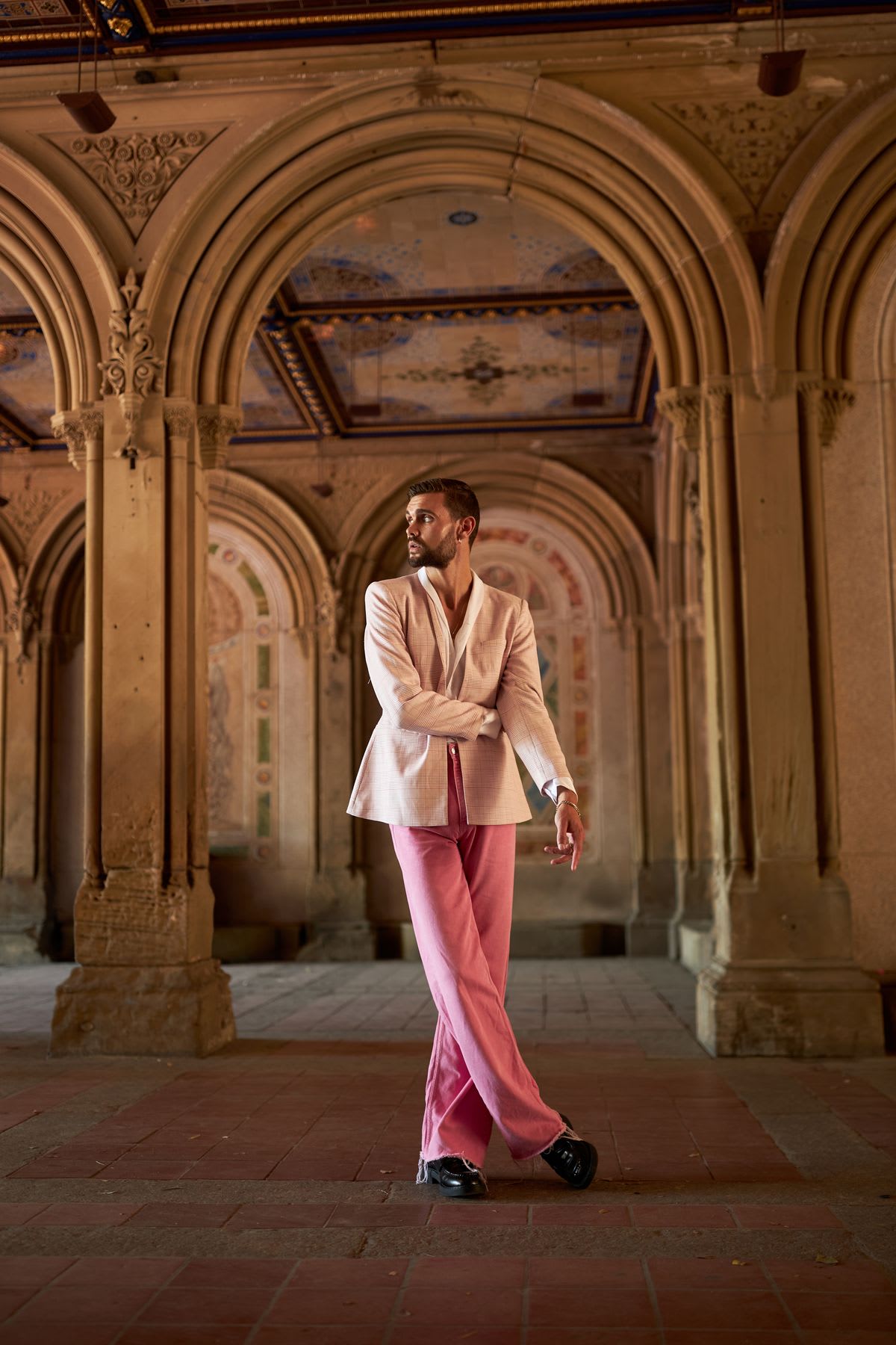 A man in upscale clothing posing in an old building