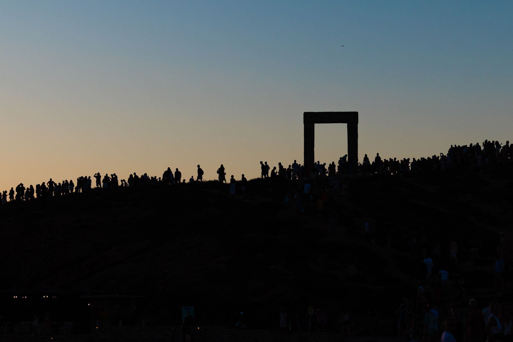 group of people are walking along a landscape at dusk