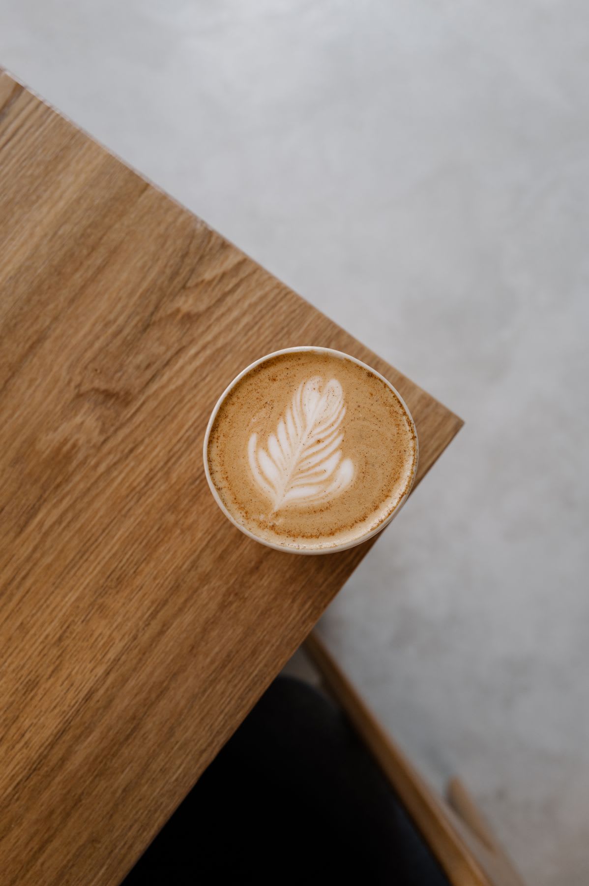 A cup of coffee with latte art on a wooden table.