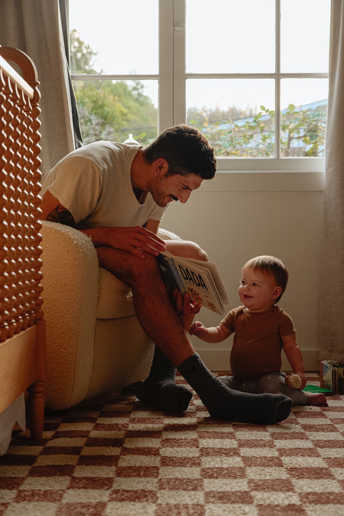 A man is sitting in an armchair reading a book to a small child.