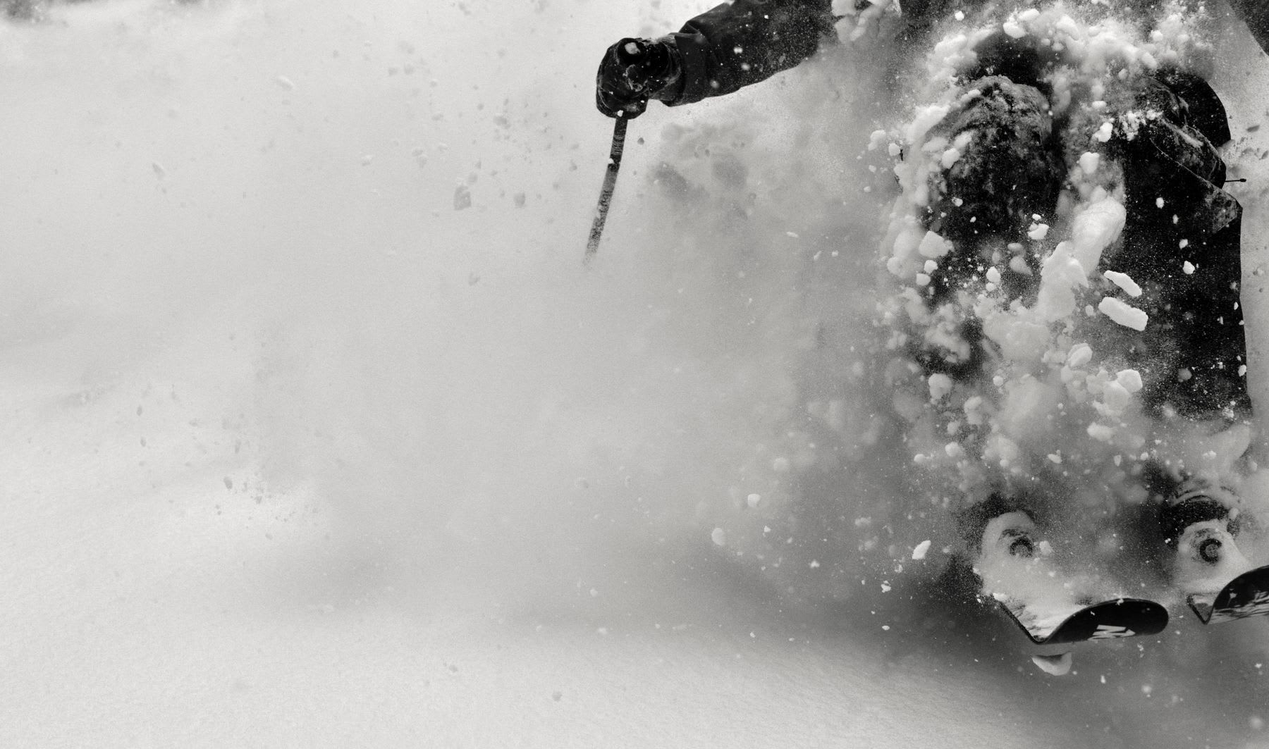 A skier kicks up snow as they travel down the hill.