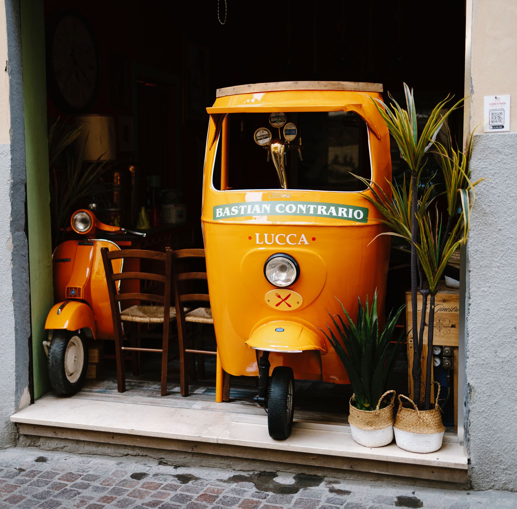 Facade of a restaurant with chairs and vintage orange motorcycles