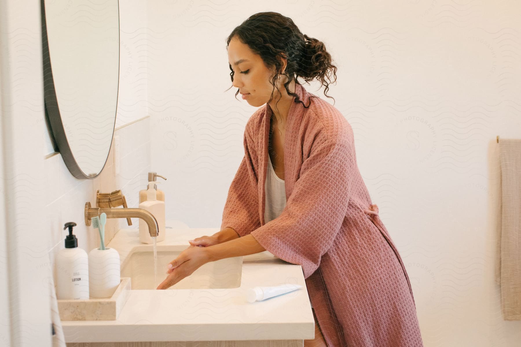 A woman washing her hands on a bathroom sink.