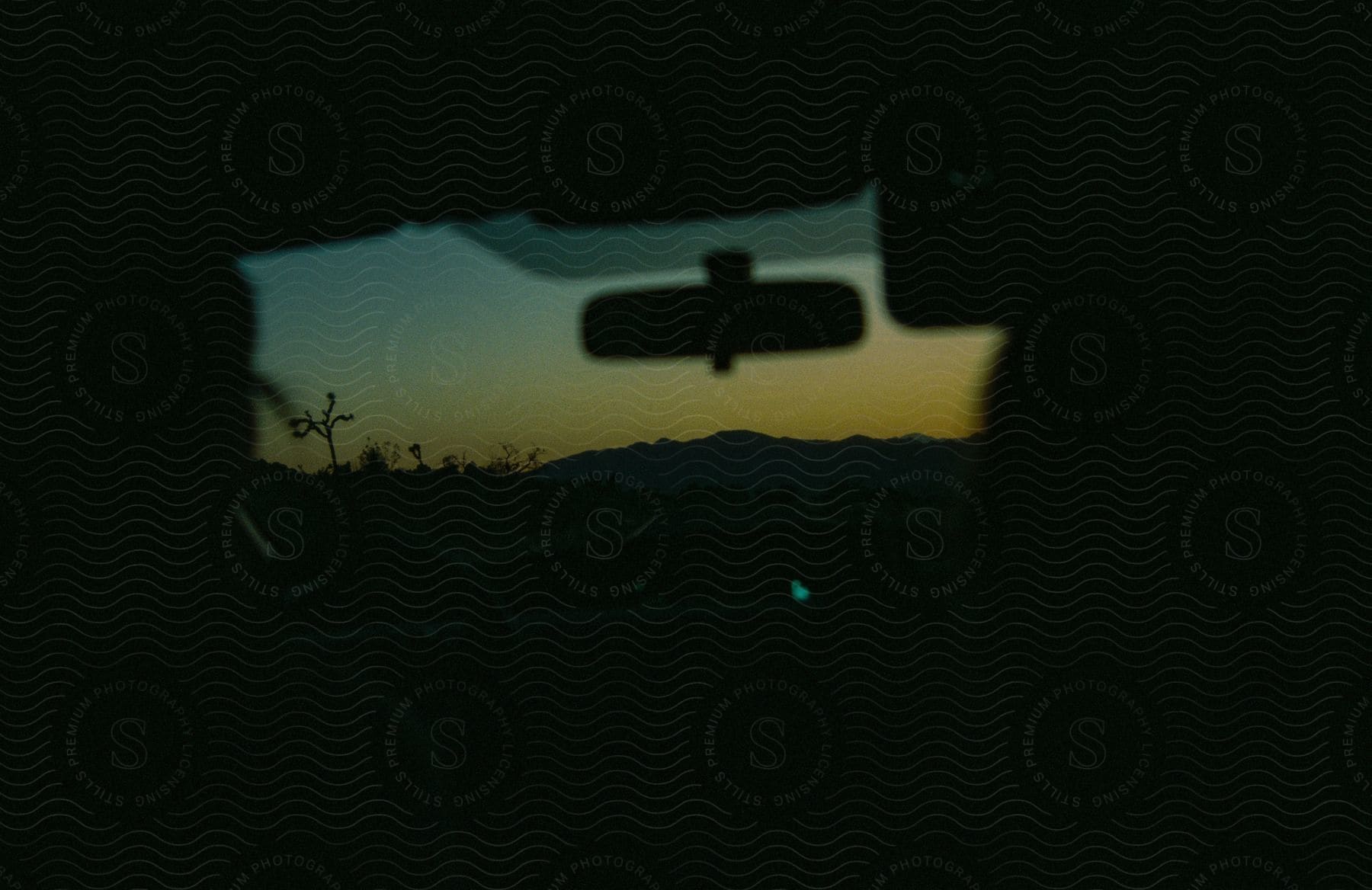 A view of a sunset out of the windshield of a car.