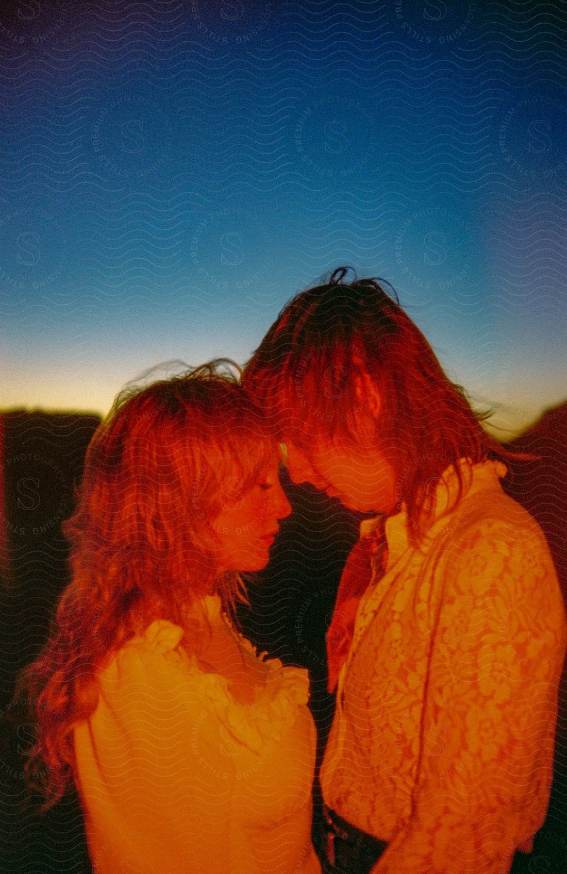 A man and woman standing outdoors at sunset.