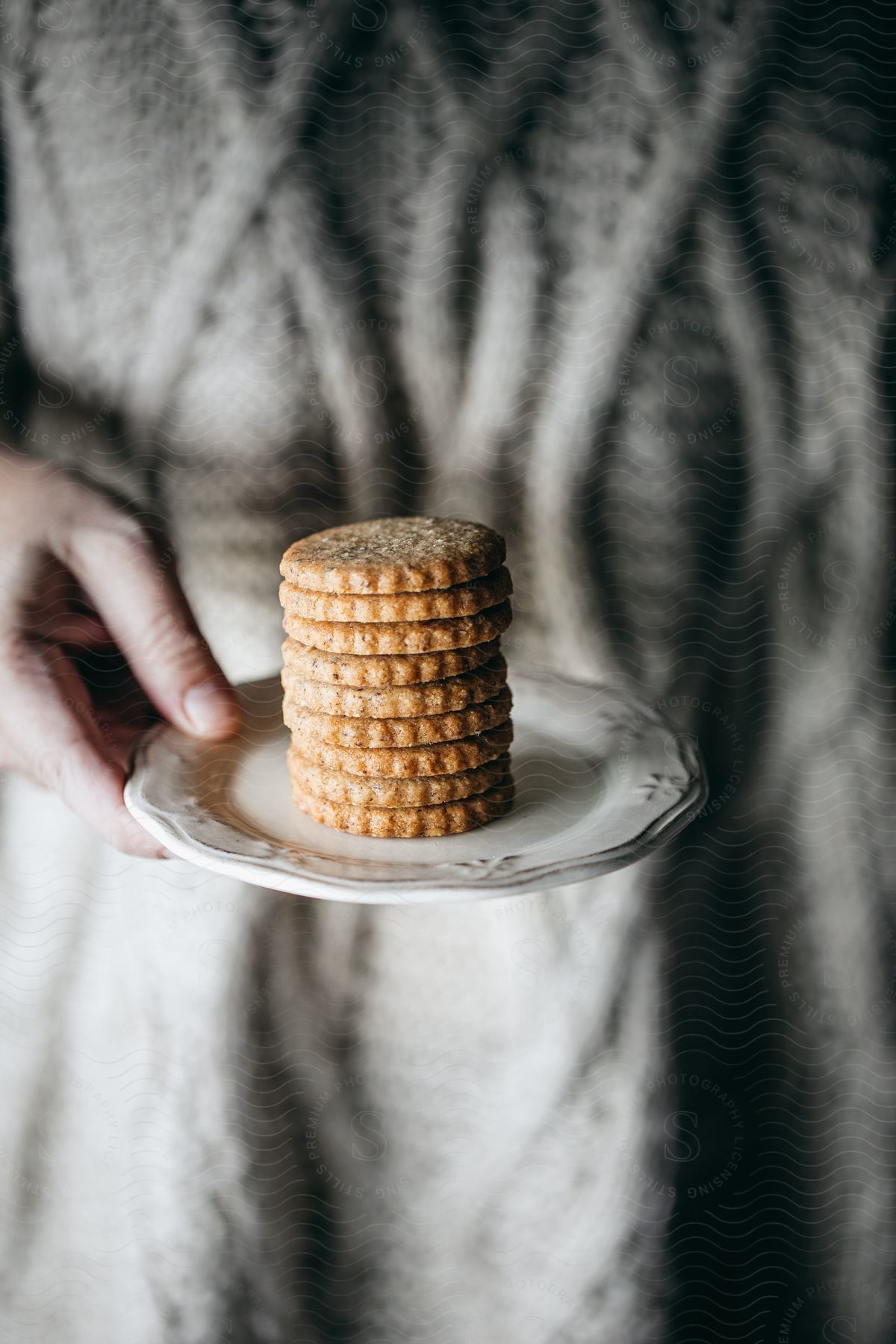 Hand of a person holding a saucer with Scottish Oat Biscuits.