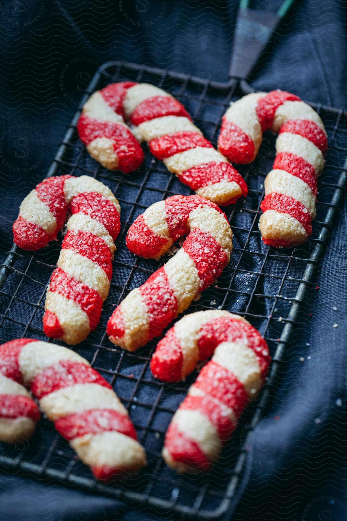 Candy cane shaped sugar cookies sit on top of a cooling rack.