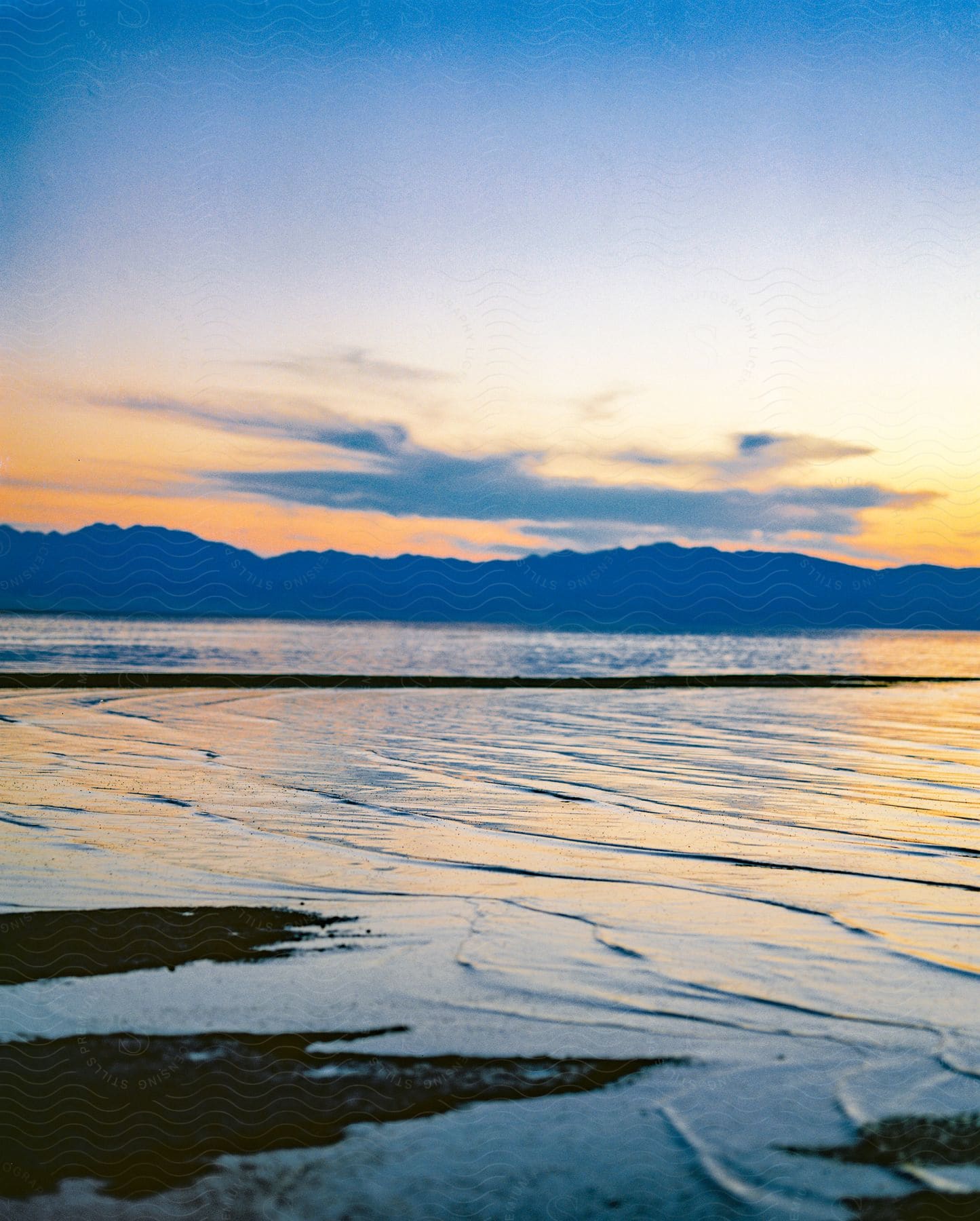 waterfront shoreline at dusk, mountains on horizon