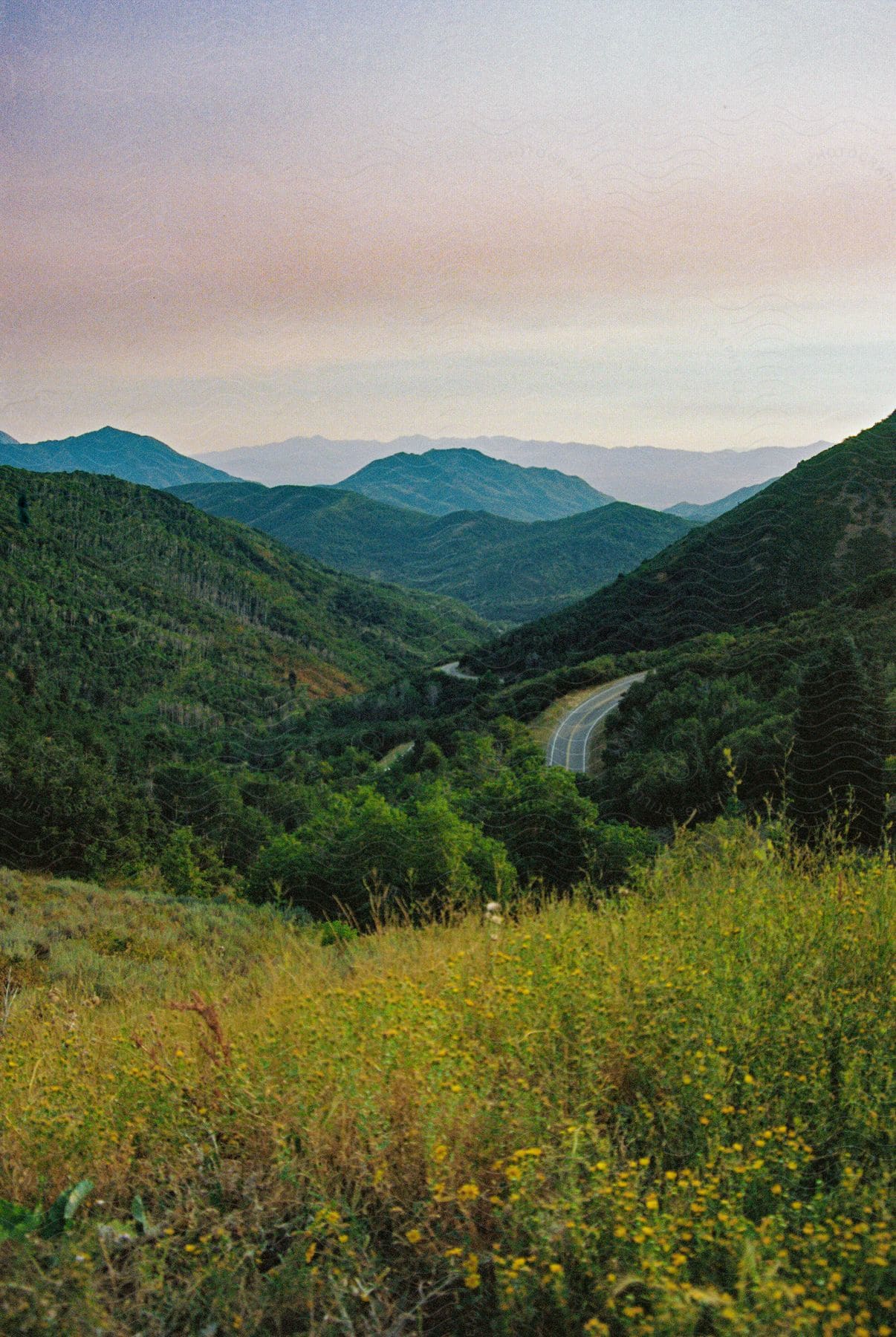 A Two-lane Highway Runs Through A Green Mountain Range