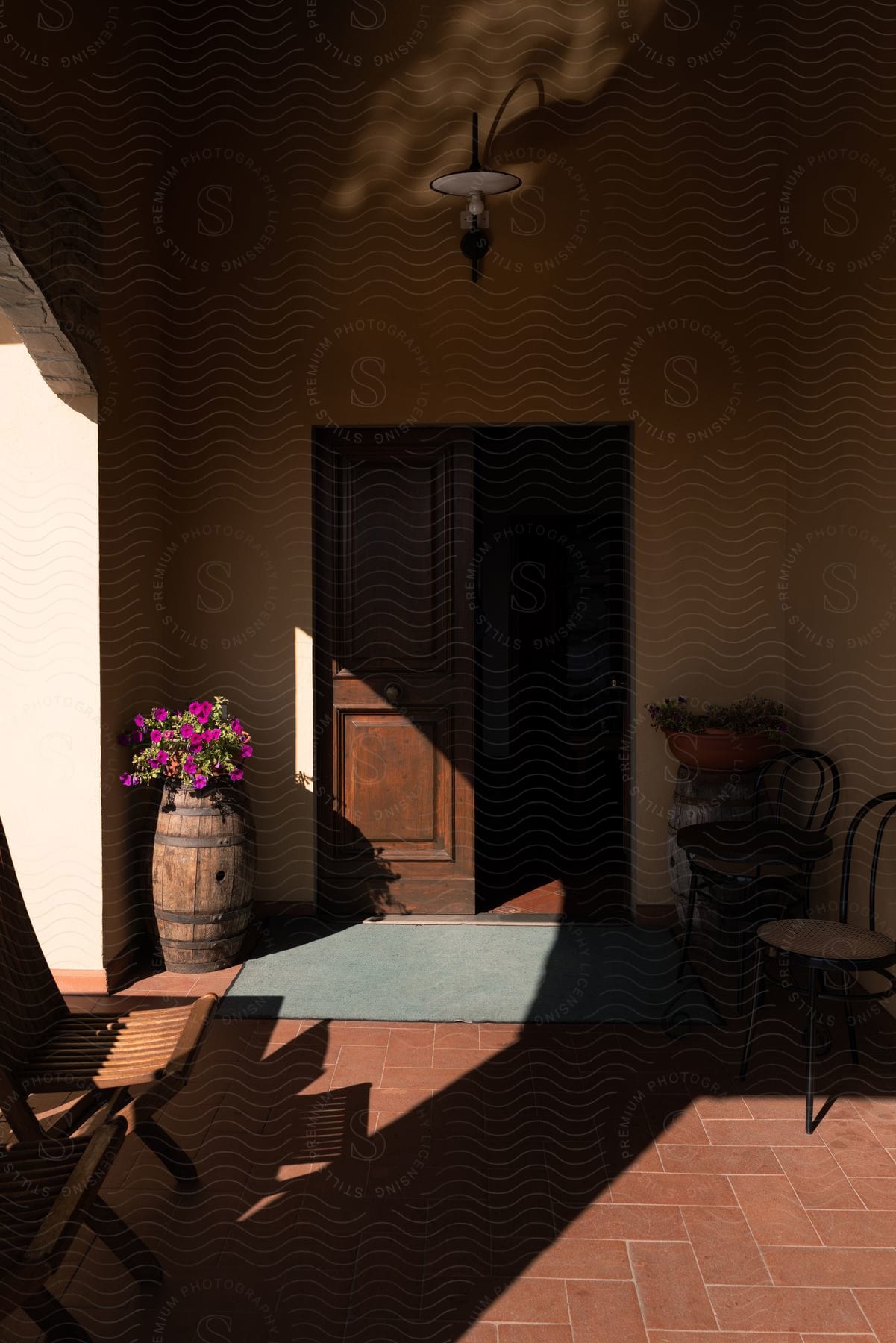 Chairs sit inside a vestibule with flowers on a barrel near the door