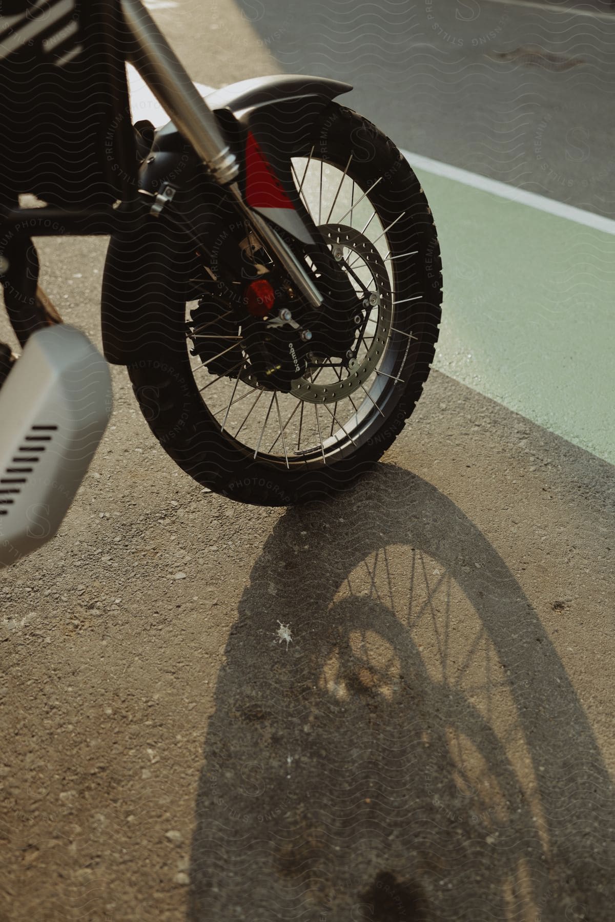 Wheel of a motorcycle projecting a shadow on the ground