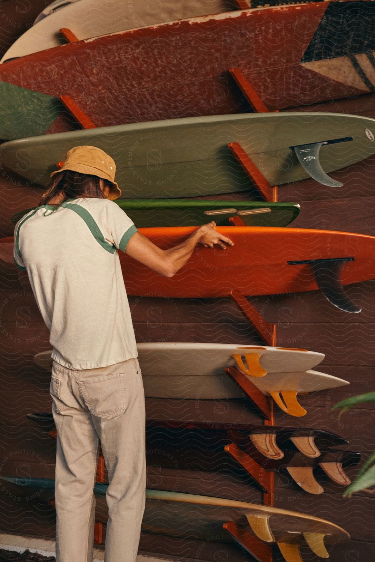 A man is hanging surfboards on the wall of a store