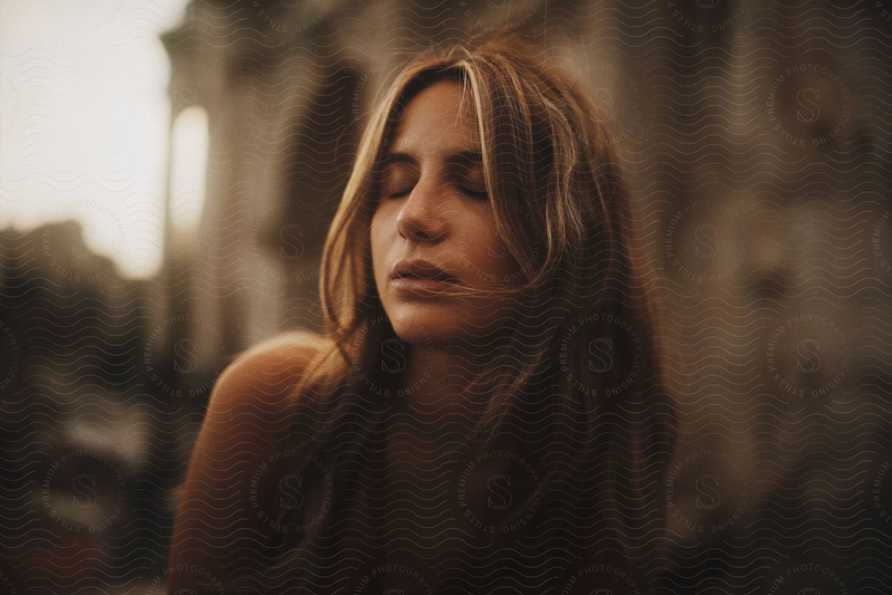 Portrait of a young woman with blonde hair and brown eyes with her eyes closed.