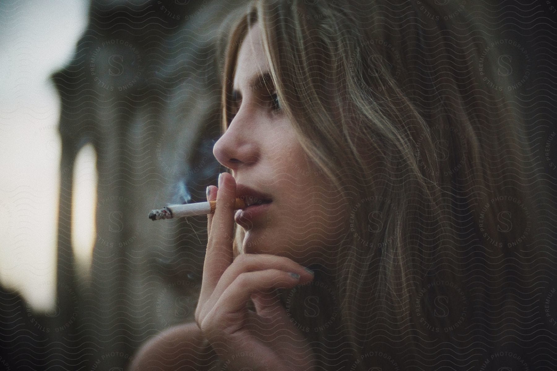 woman smoke cigarette, head turned in profile, outdoors