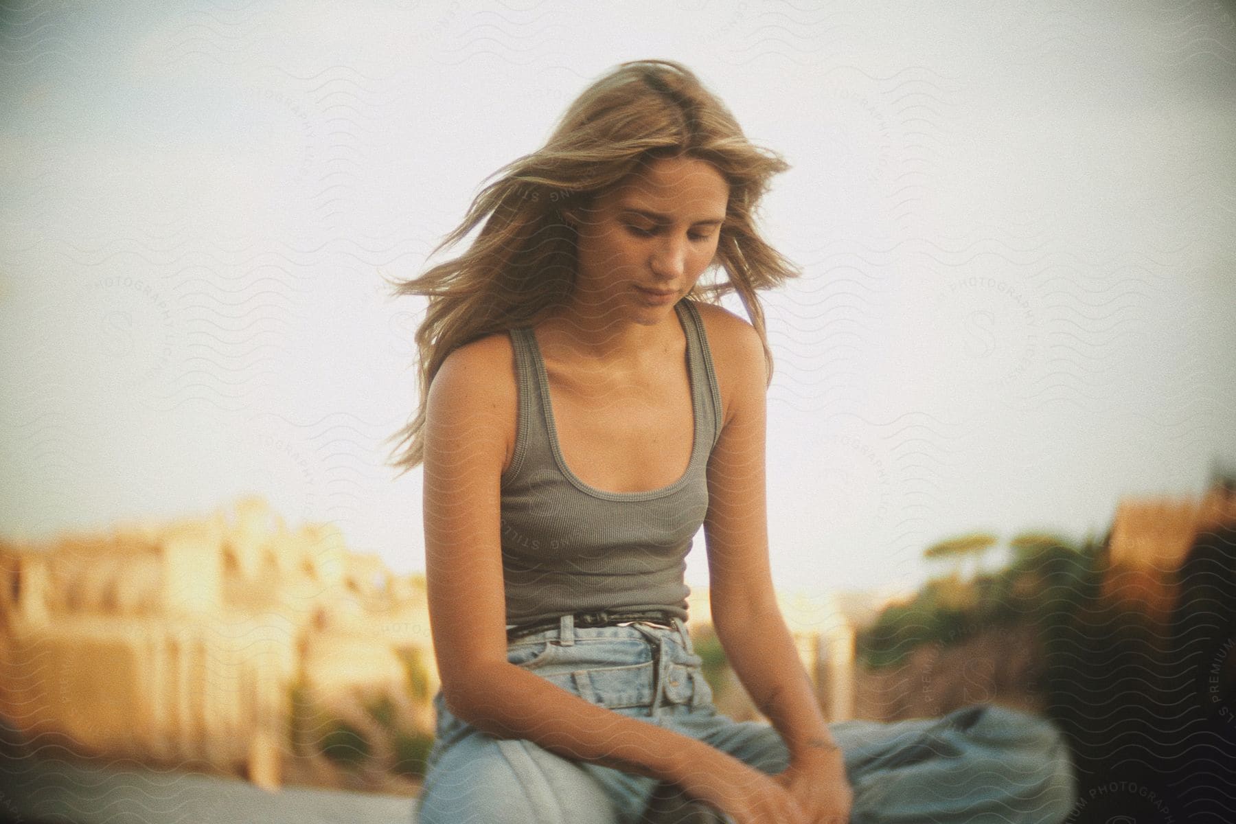 Young woman with blonde hair, sitting with a neutral facial expression.