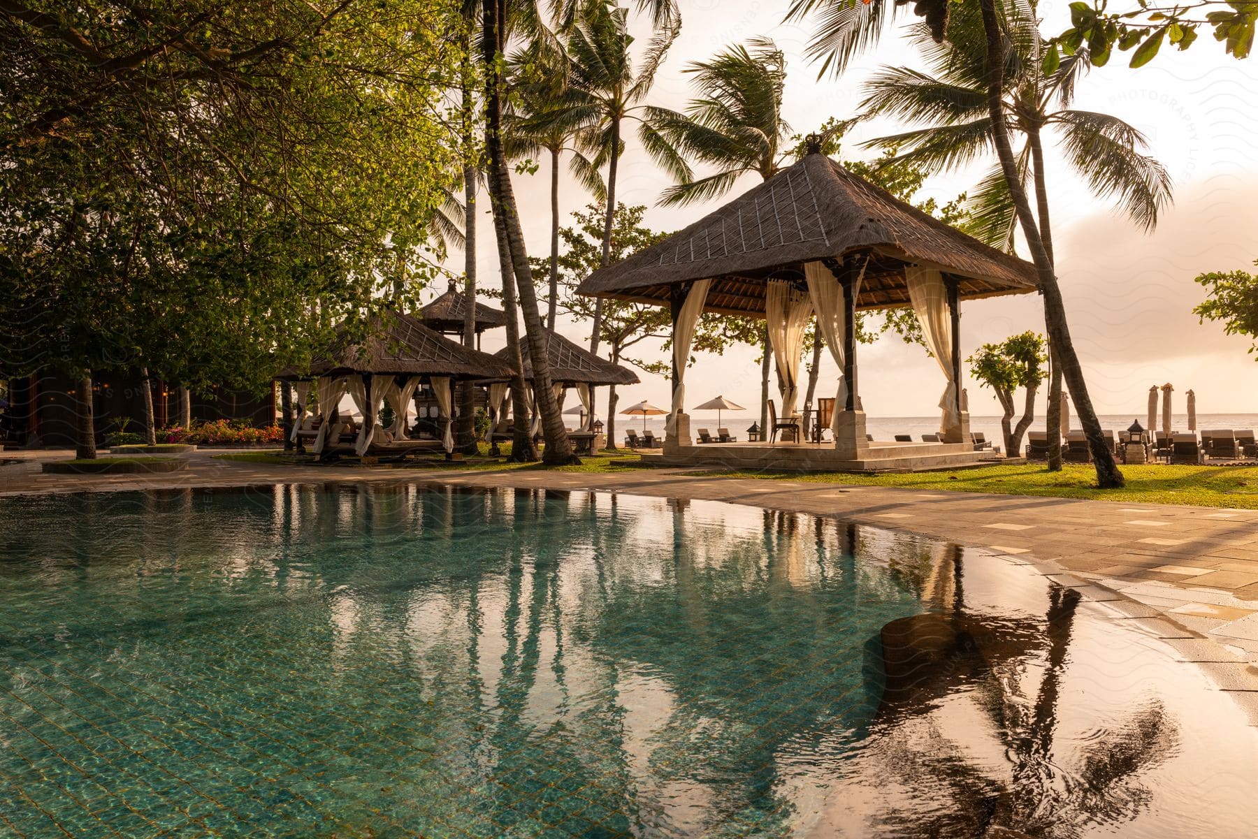 Small pavilions sit between large reflective pool and beach at resort.