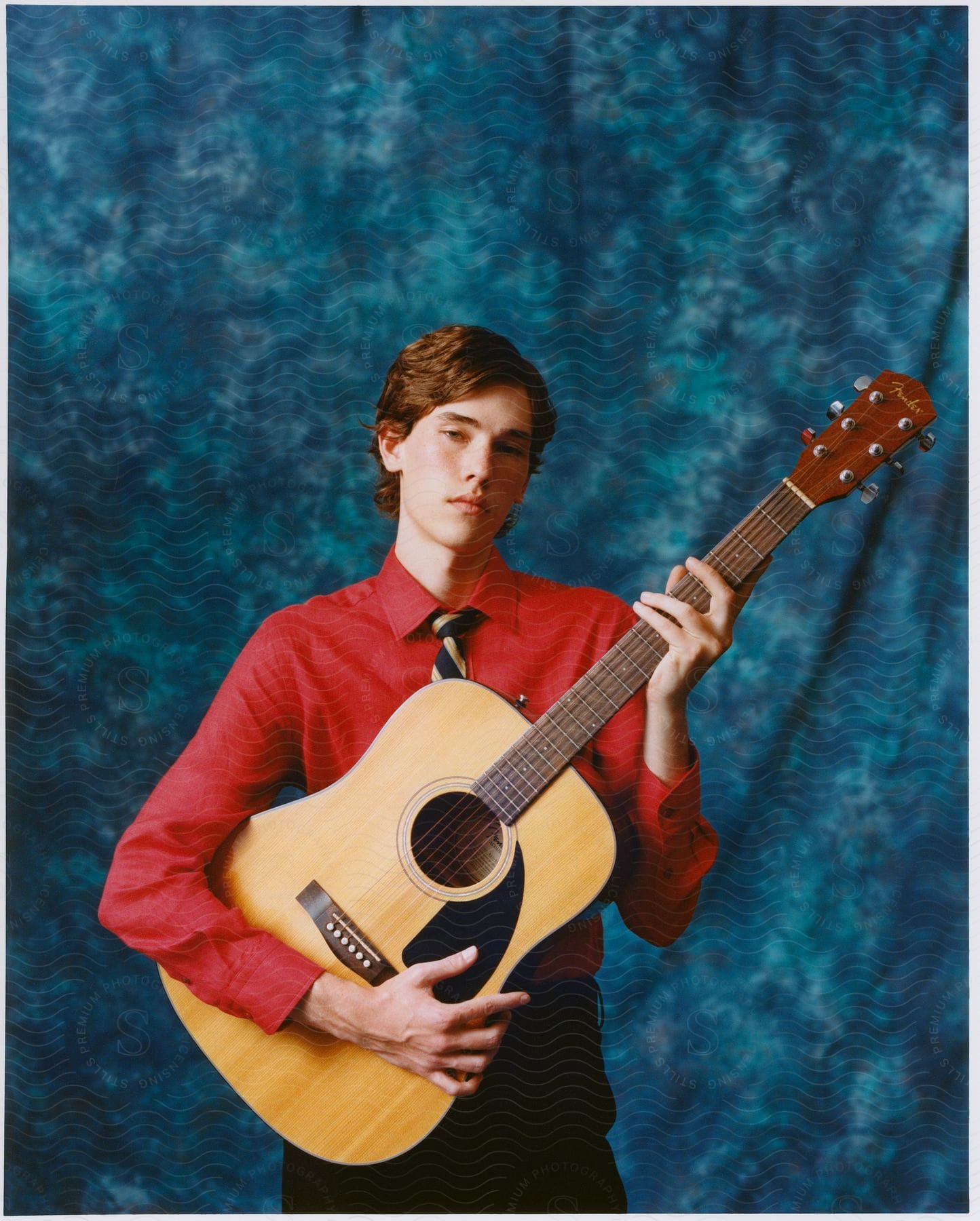 Young man posing with a guitar in his hands.