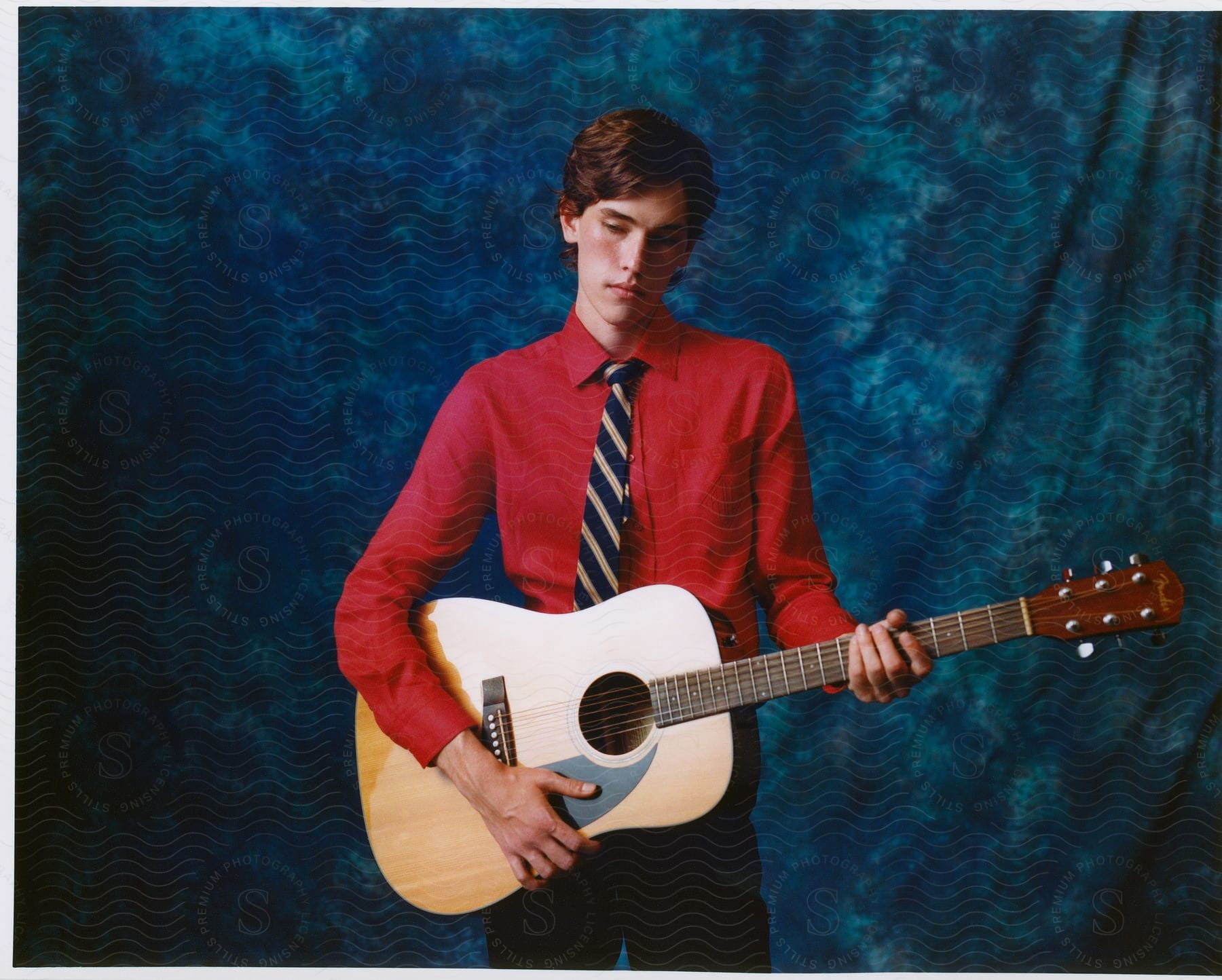 Young man posing with a guitar in his hands.