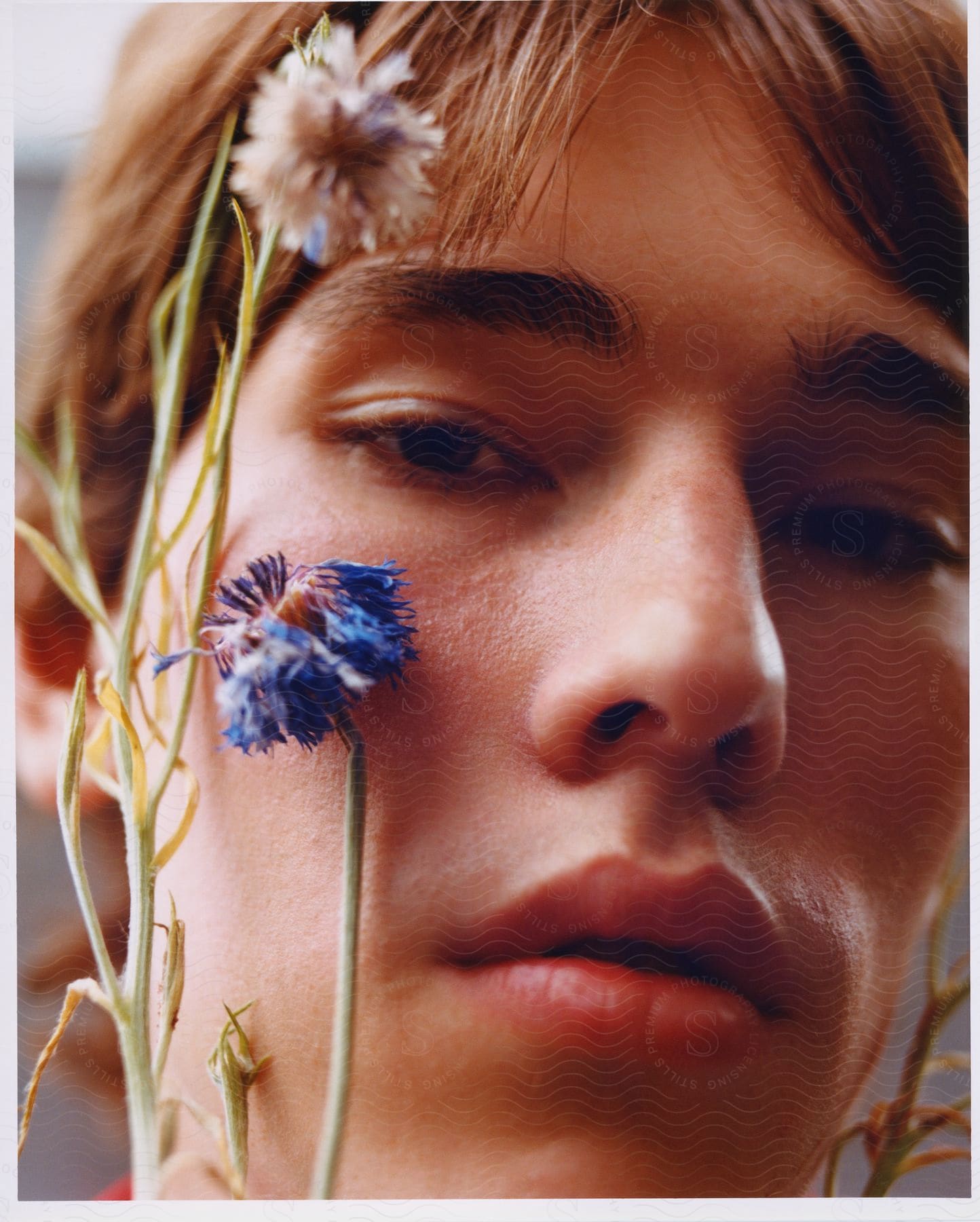 female with short brown hair poses with flowers framing face