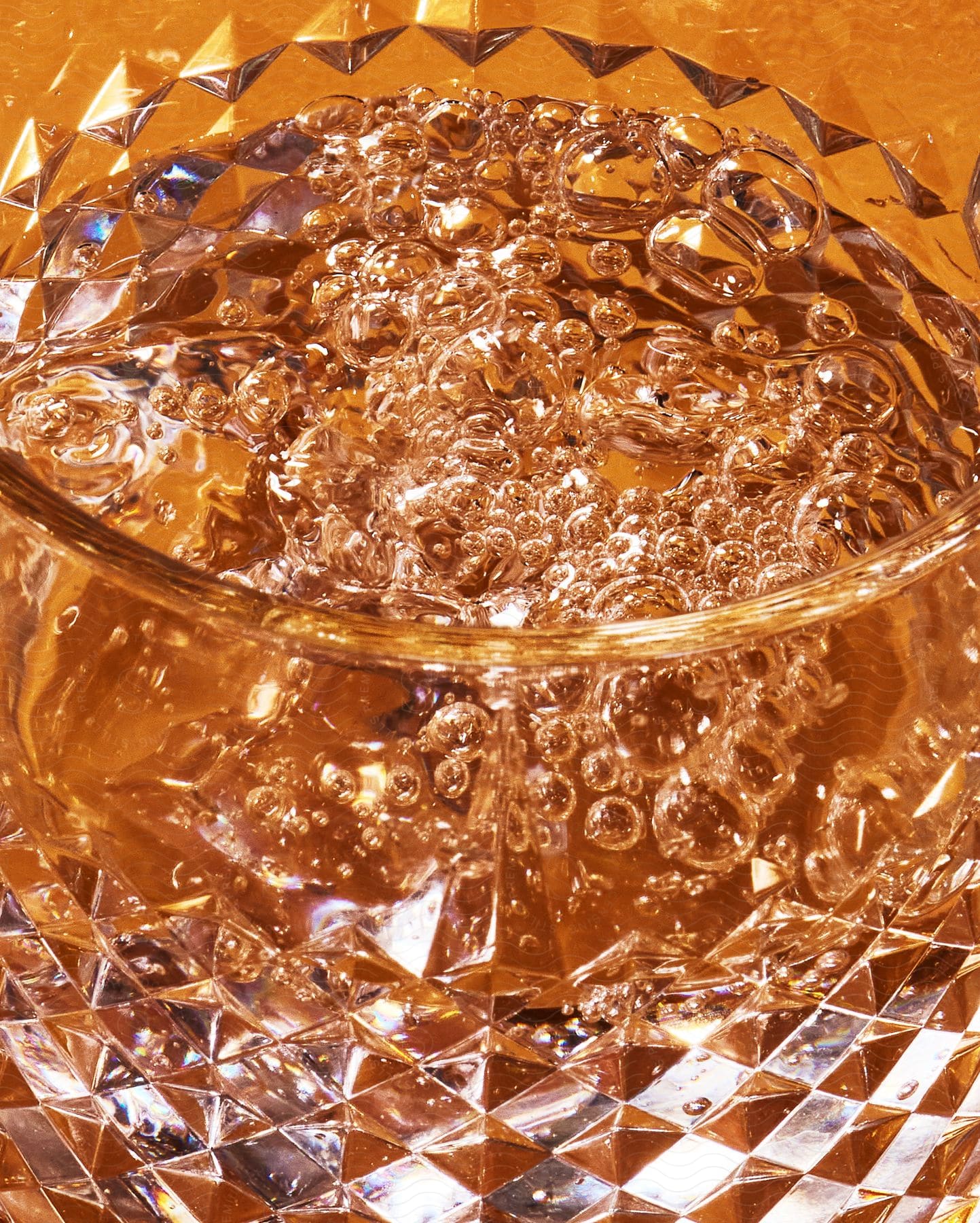 A glass cup with clear liquid full of bubbles.