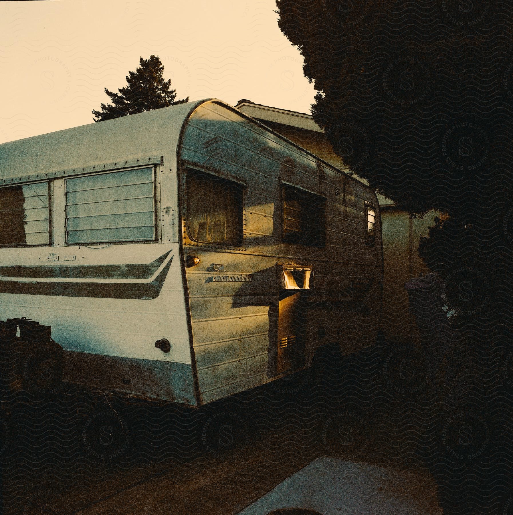 Motorhome sits parked in driveway of house under a red tinted sky.