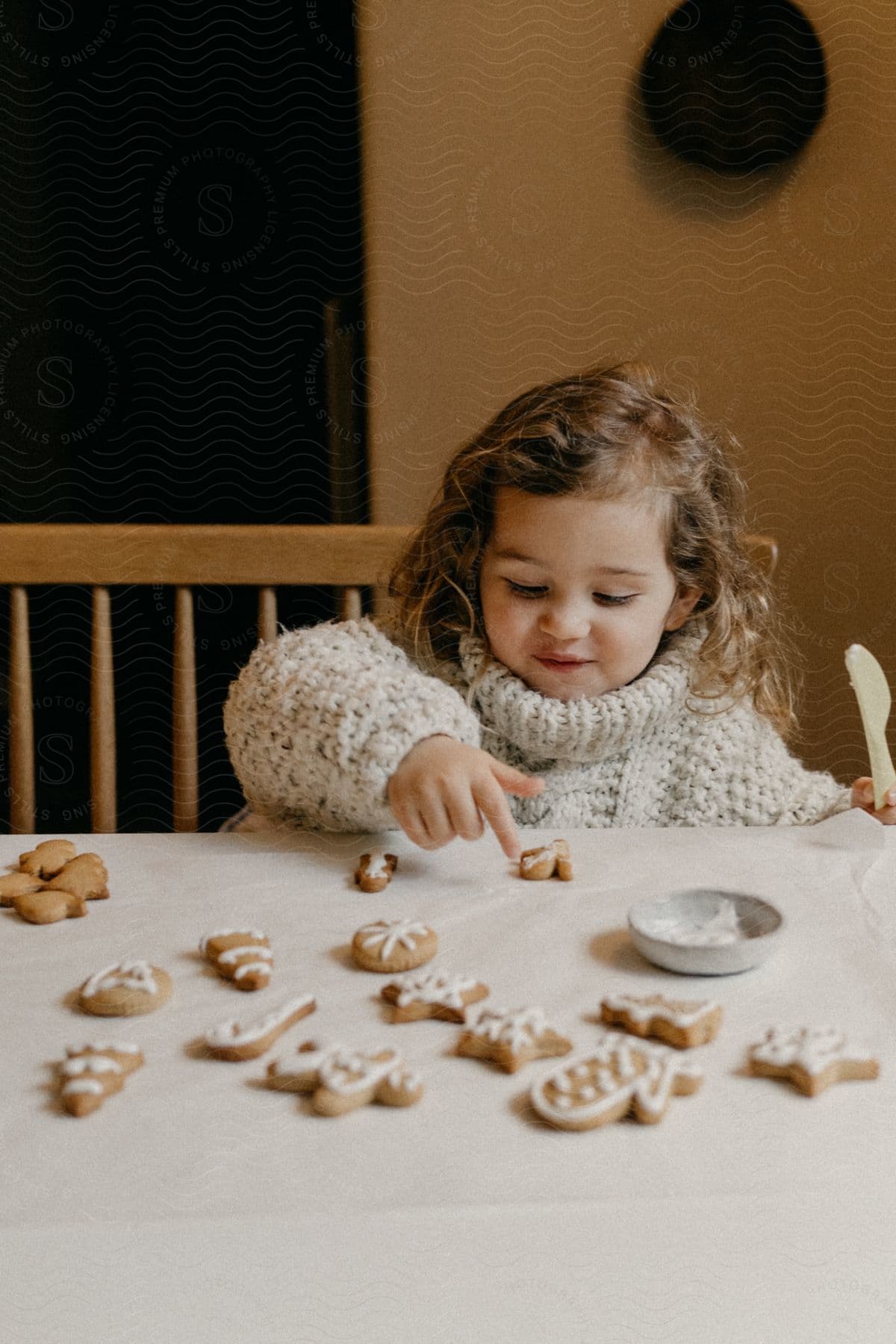 Girl wearing a sweater plays with cookies