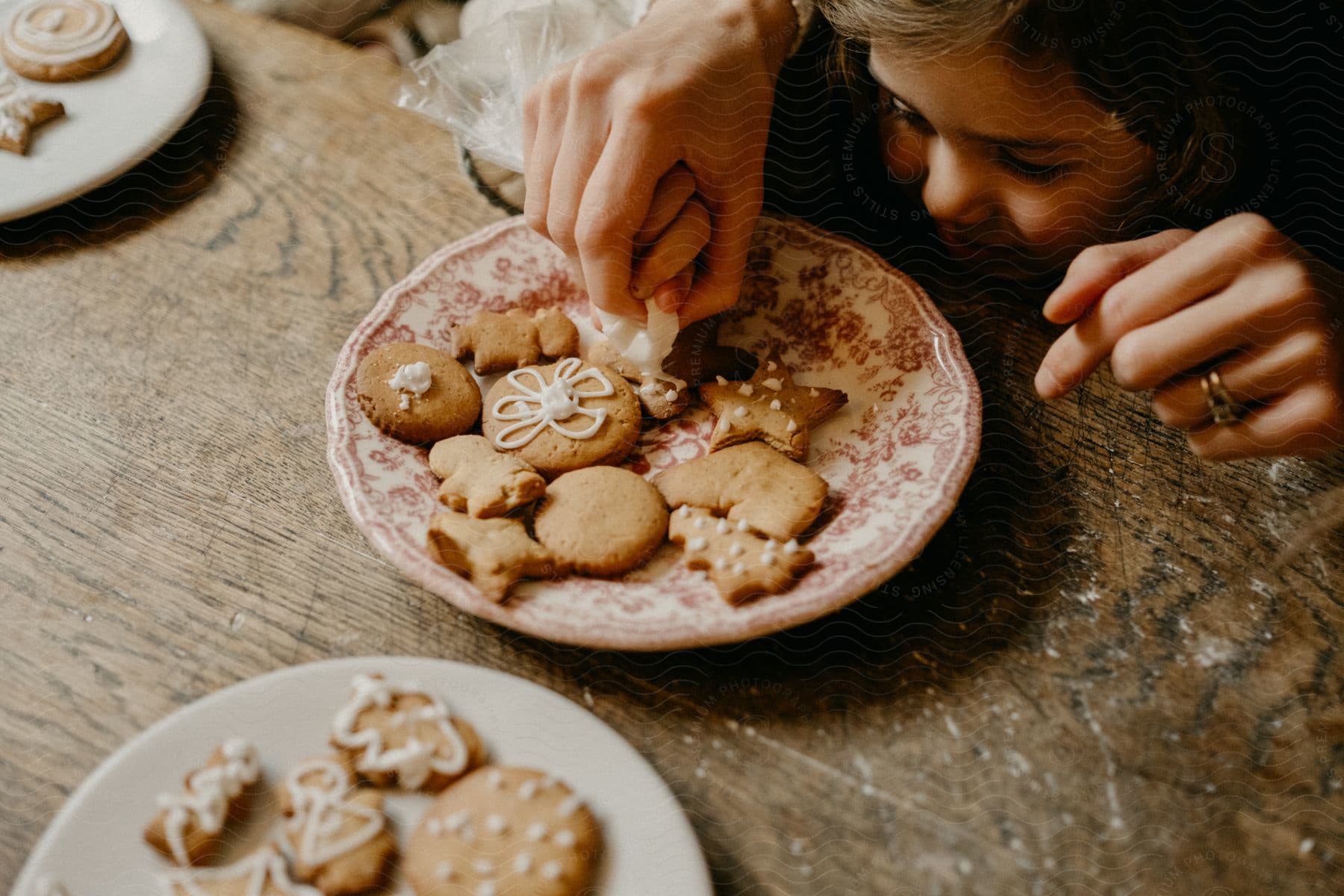 A girl with a plate of cookies on the wooden table.