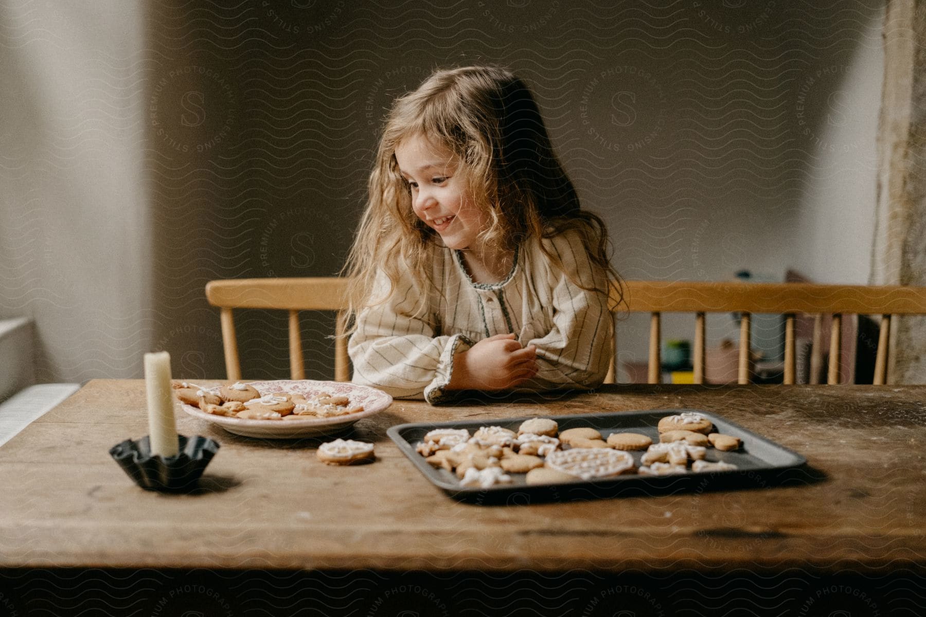 Girl at the table looking at a plate of cookies.