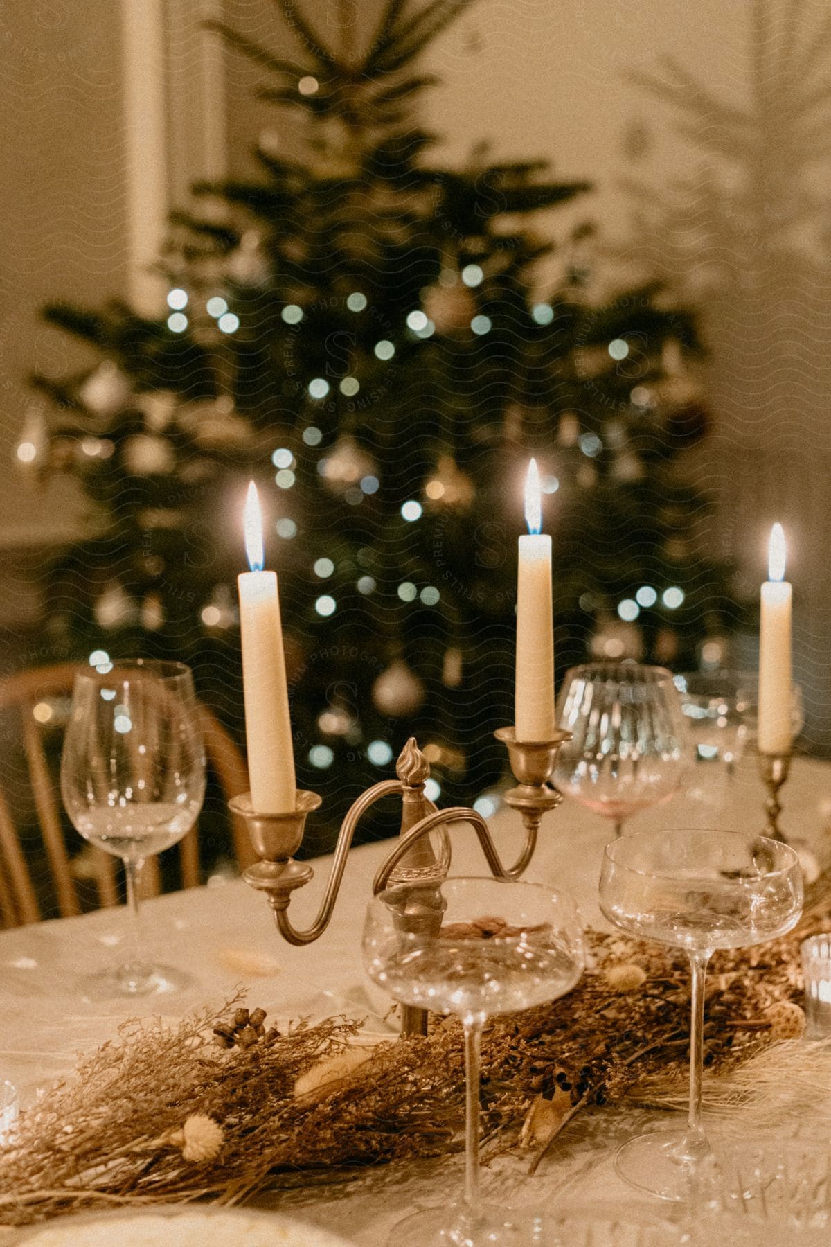 a beautifully set table with candles, wine glasses, and a Christmas tree in the background.