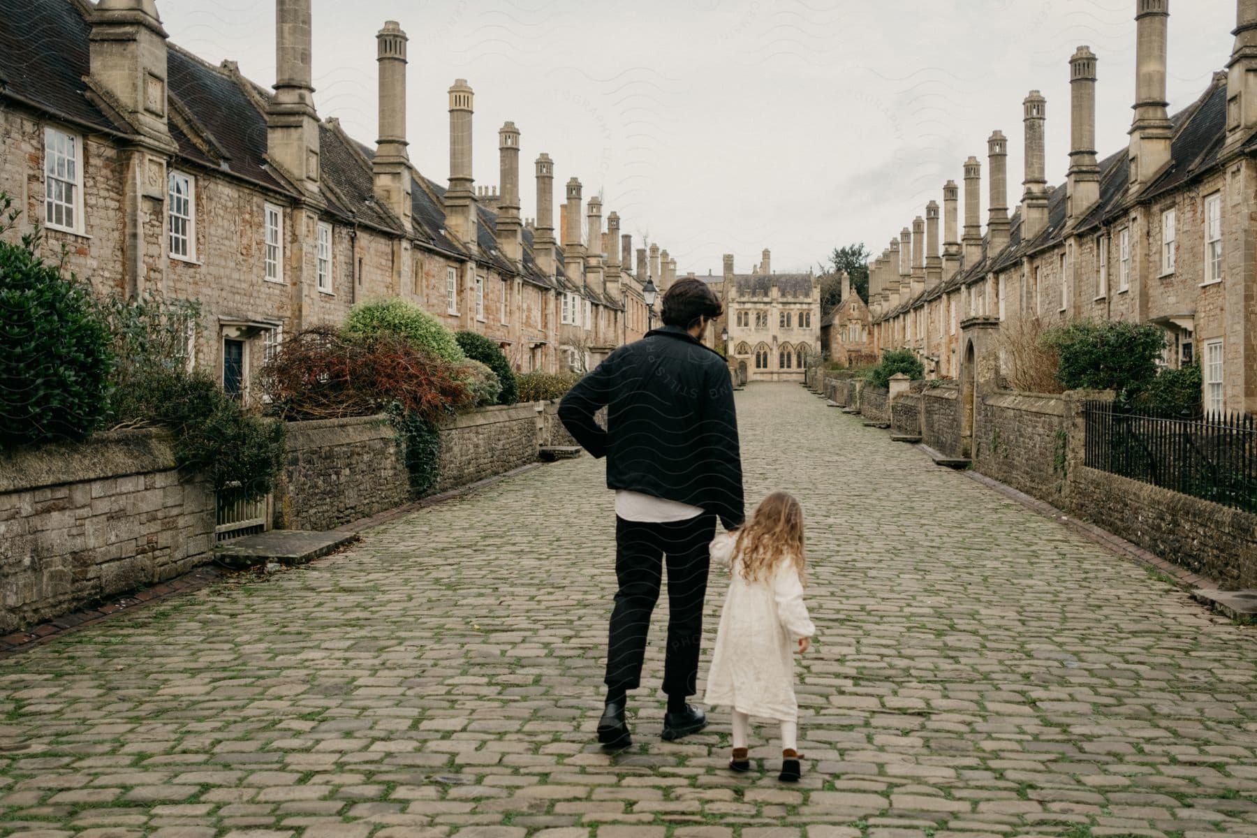 Father walking hand in hand with his daughter on Vicar's Close street.