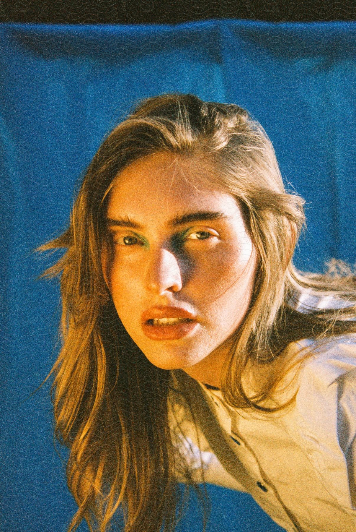 Light shines on the face of a woman with long blonde hair as she leans down and looks ahead