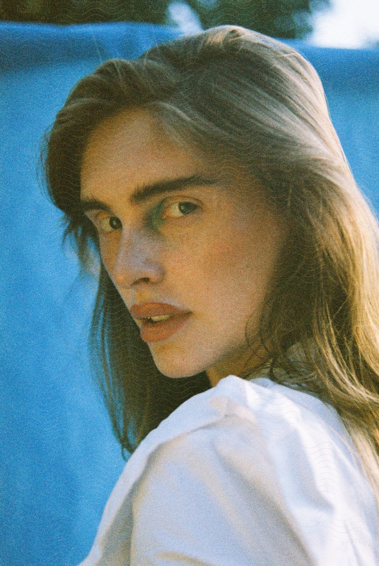 Young adult with full hair in a white dress at mid-day