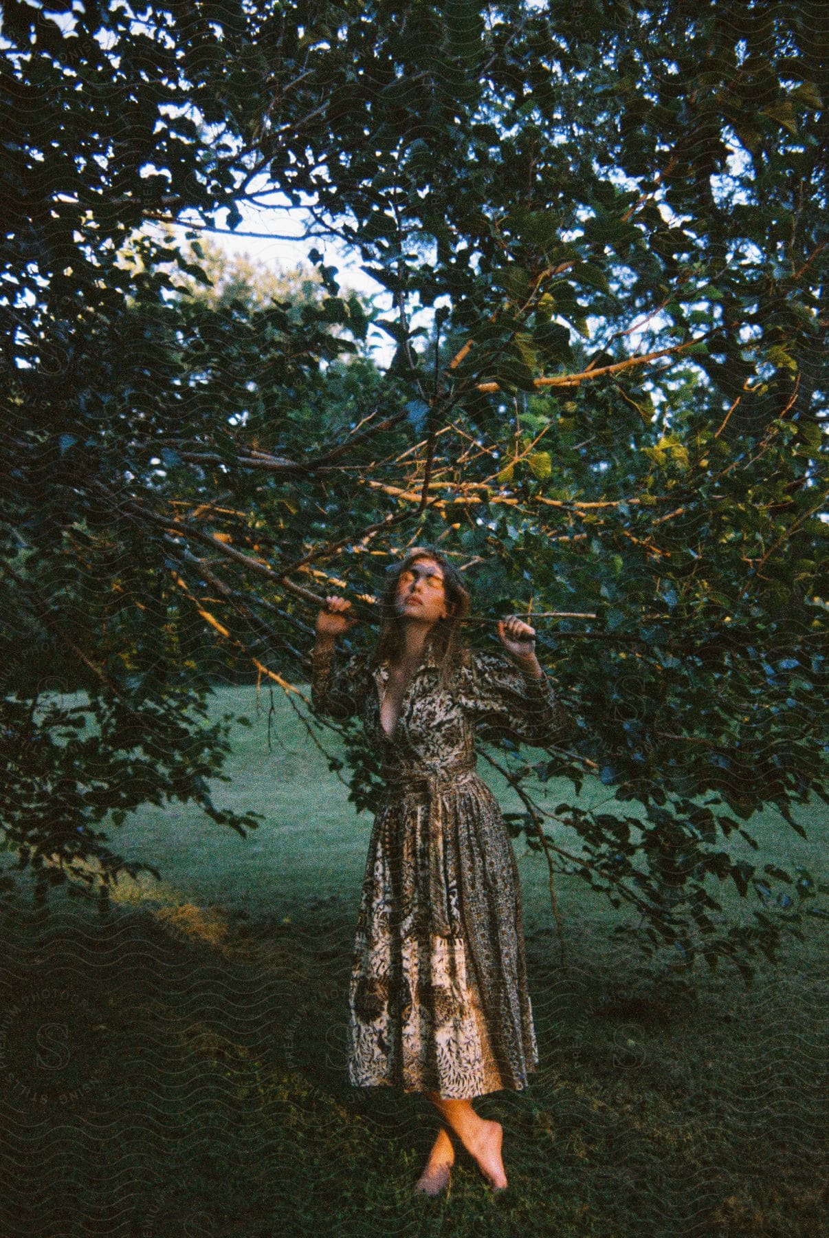 Woman models dress outdoors near tree