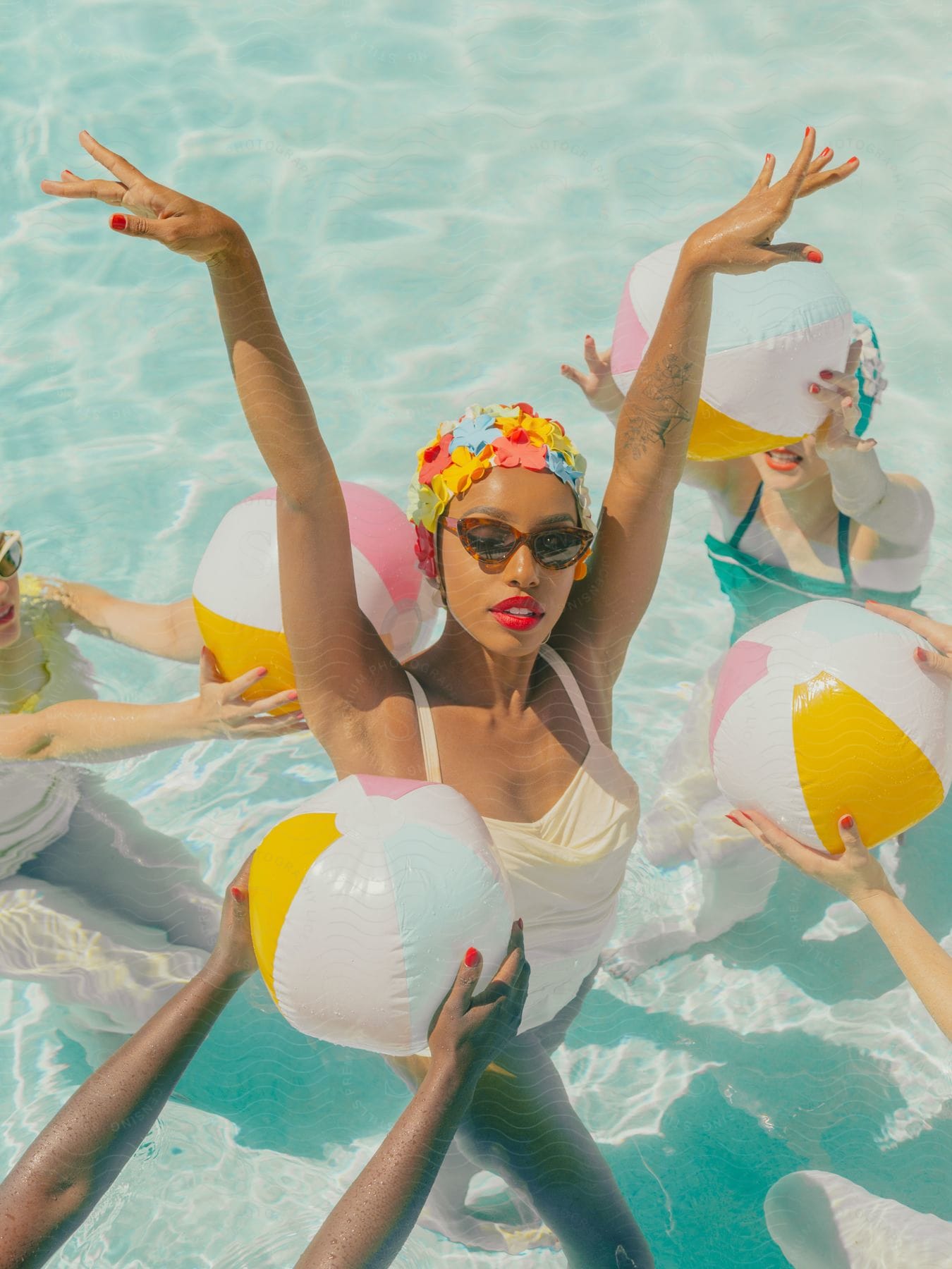 A young, black woman models swimming accessories with several other models in a swimming pool.