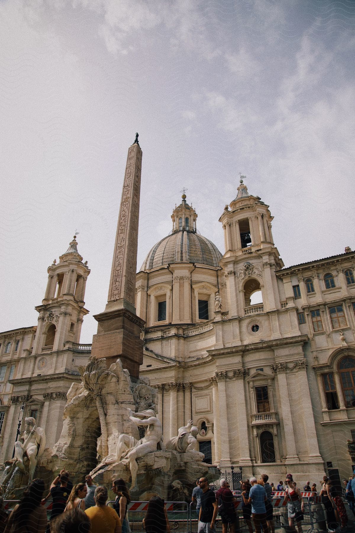 A building with ancient architecture with a tower at the front and several tourists below.