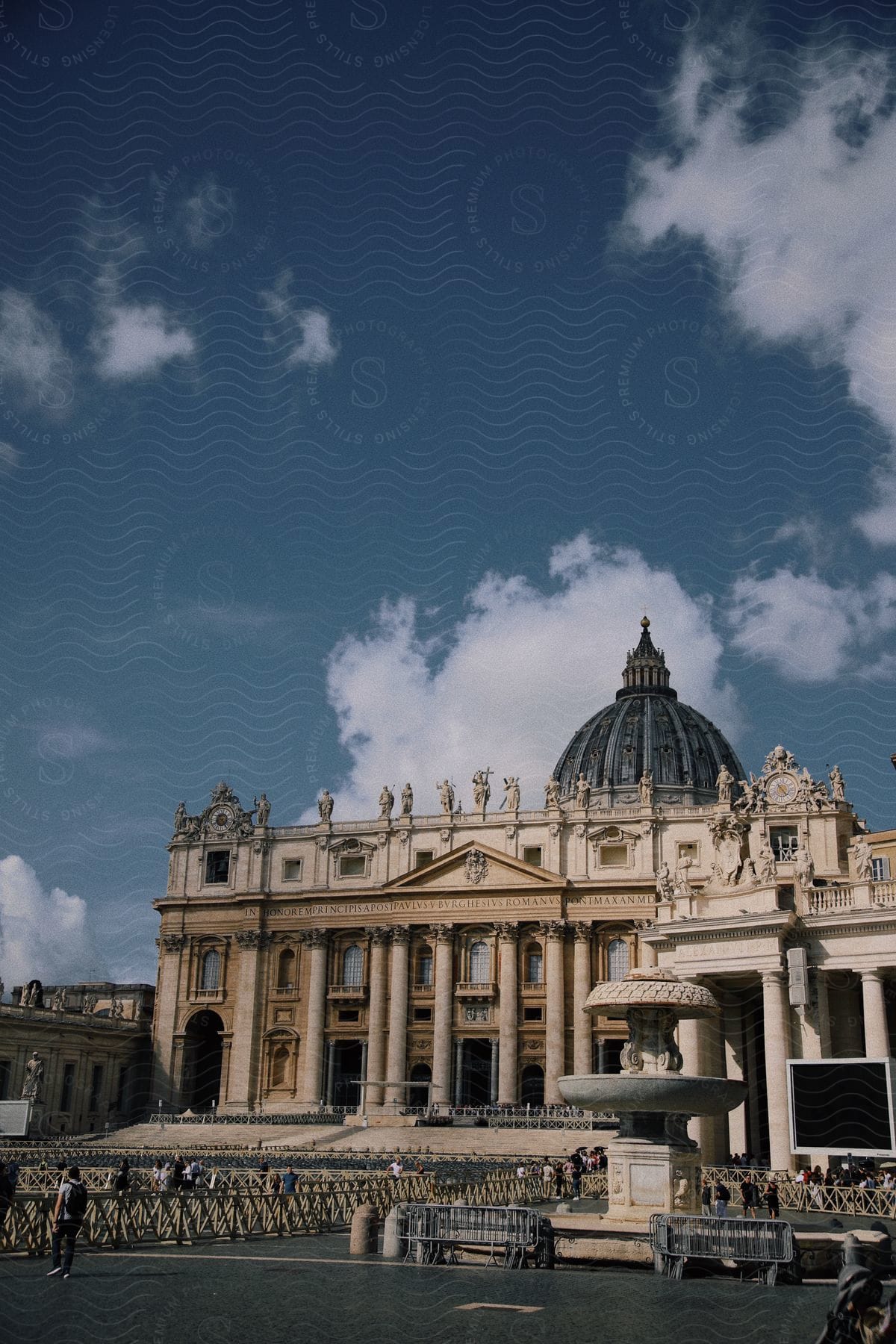 The ornate architecture of St. Peter's Basilica attracts numerous tourists who are lined up to enter.