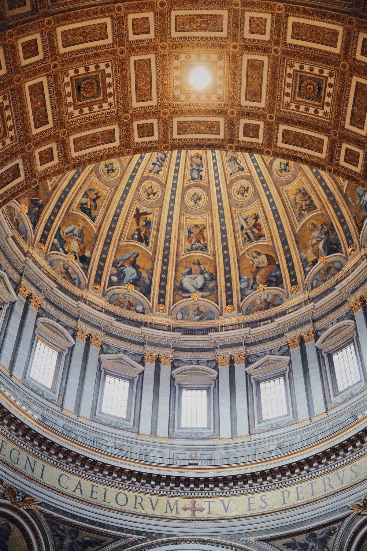 The ceiling of a large church with painted murals on it.