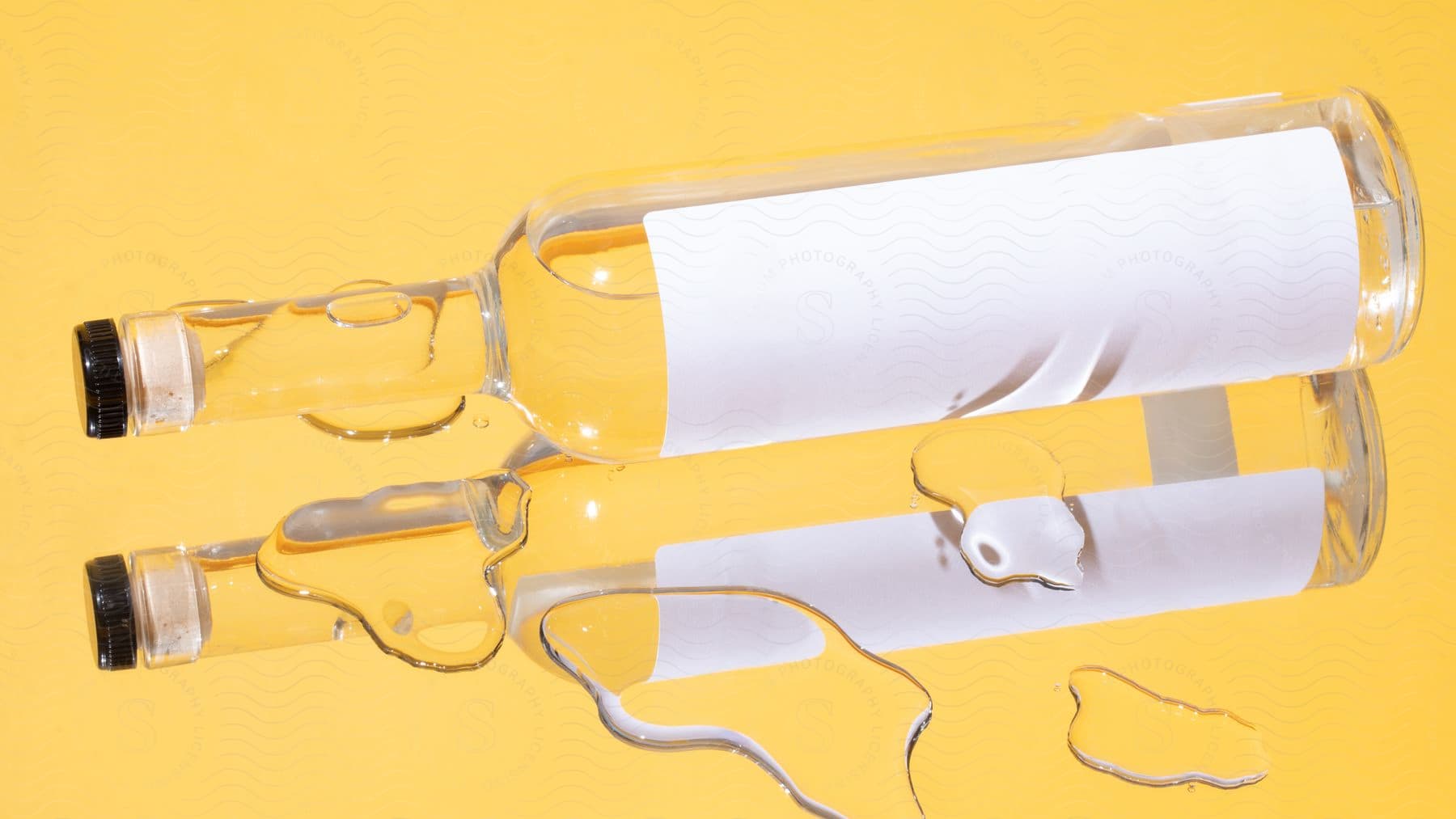 Two bottles of alcohol displayed against a vivid yellow background