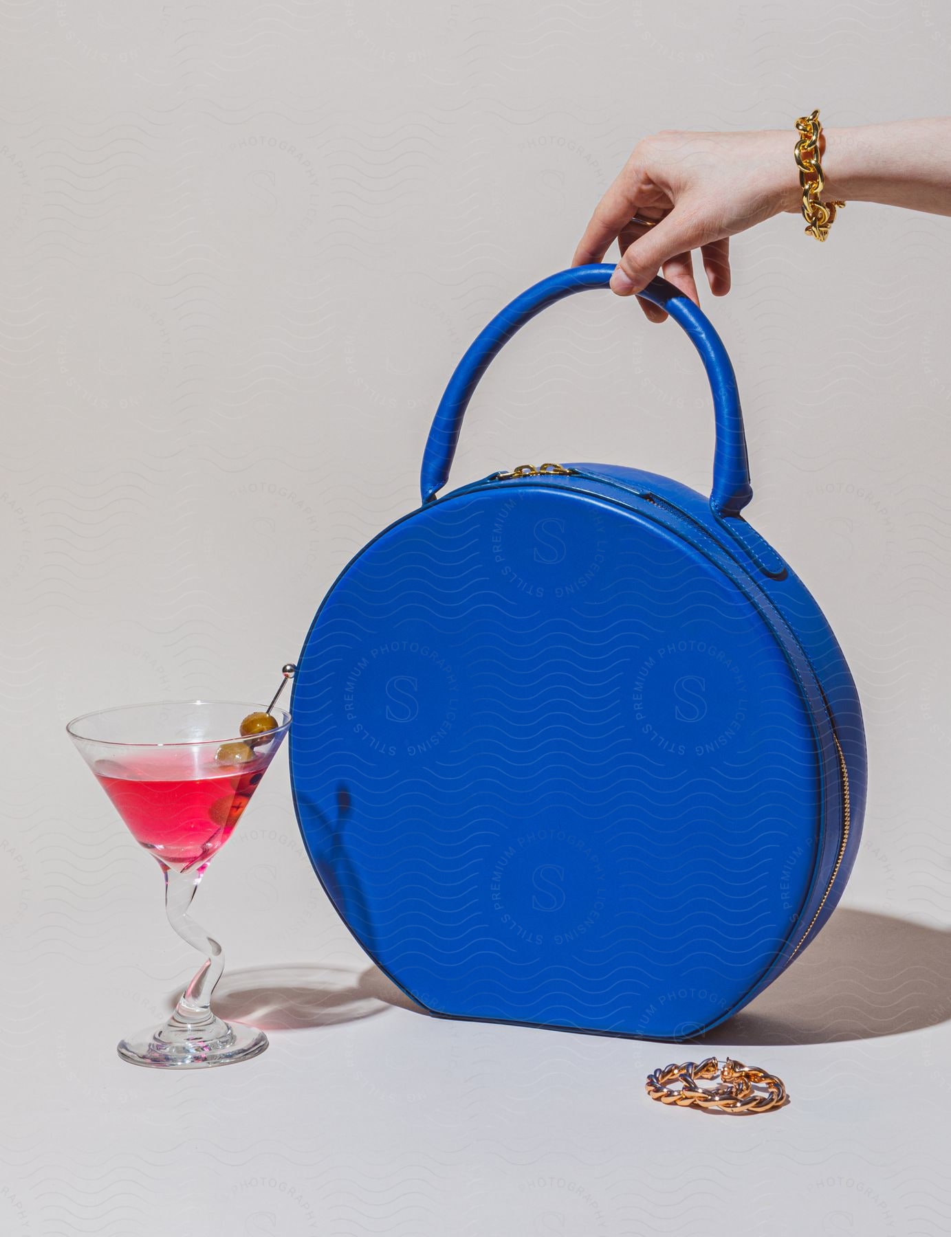 Blue leather circle bag next to a cocktail glass.