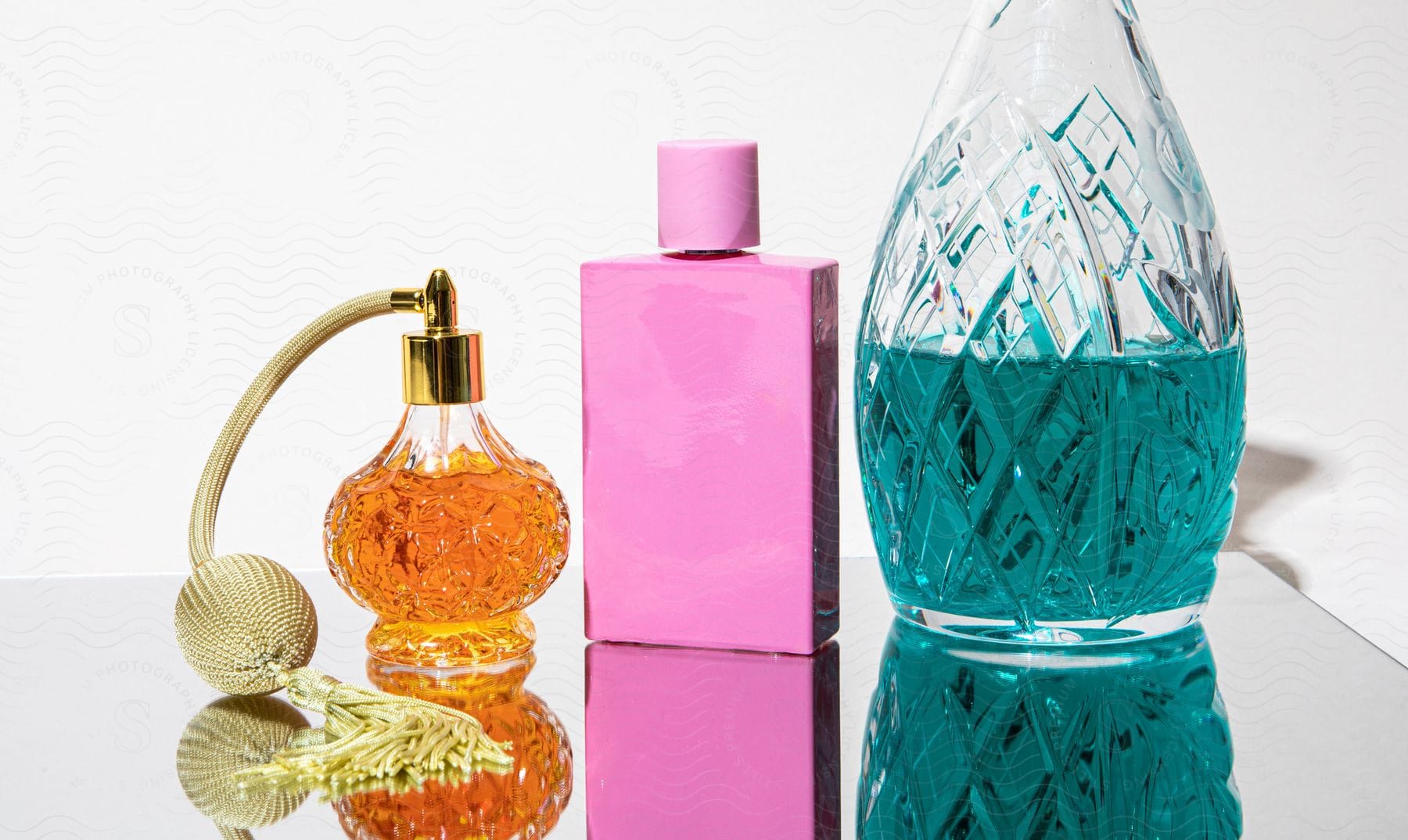 A Glass Perfume Bottle If Filled With Orange Liquid And Is Next To A Pink Bottle And Tall Glass Bottle