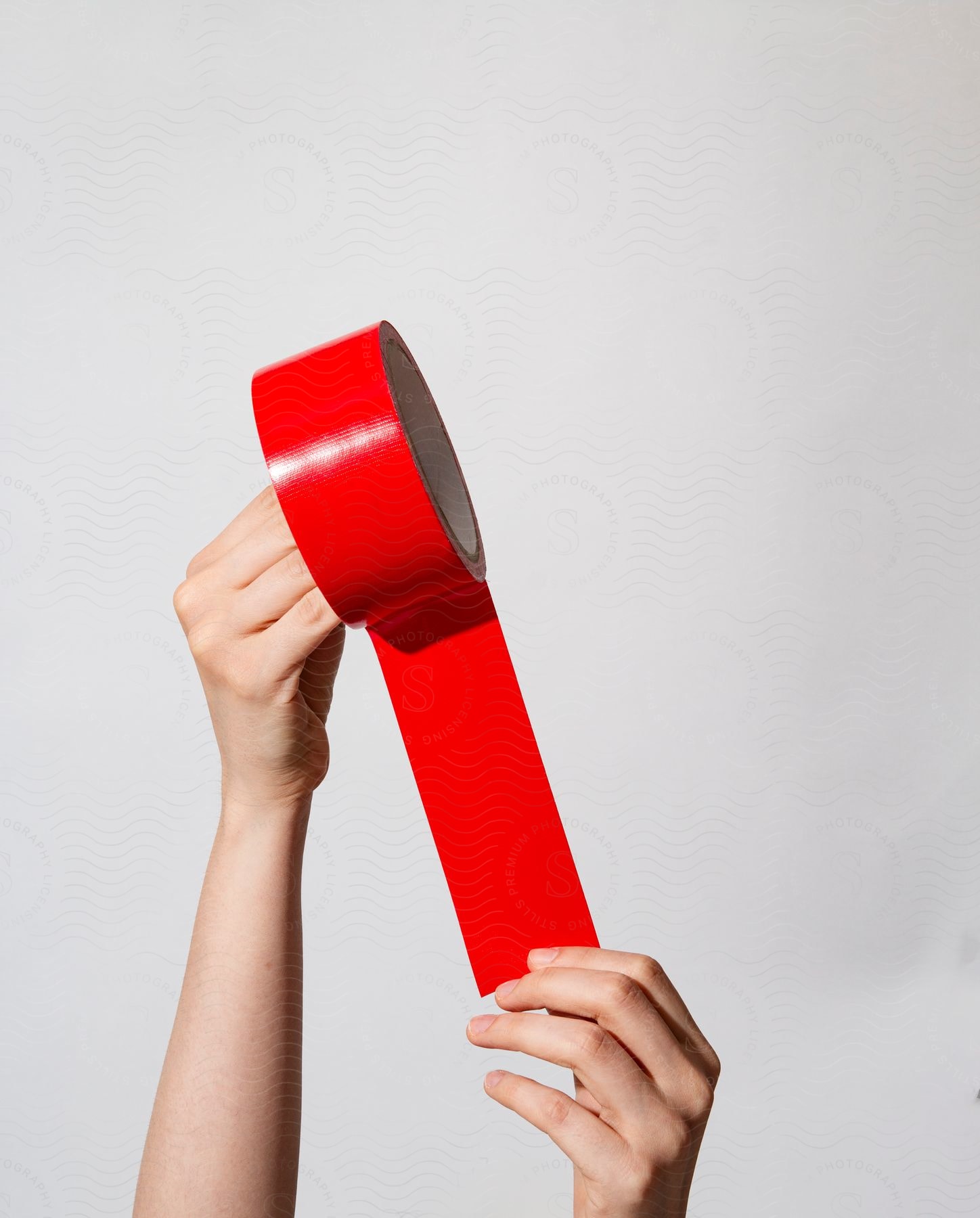 A girls hands are holding up a roll of red tape