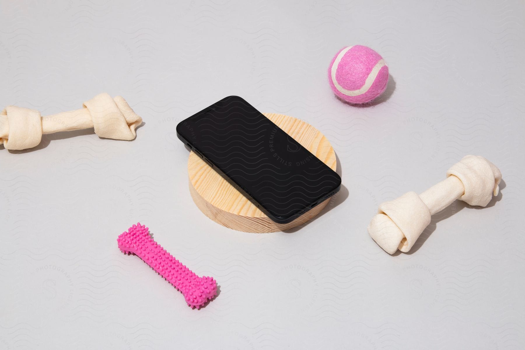 Stock photo of a smartphone sitting on a table with some dog toys around it.