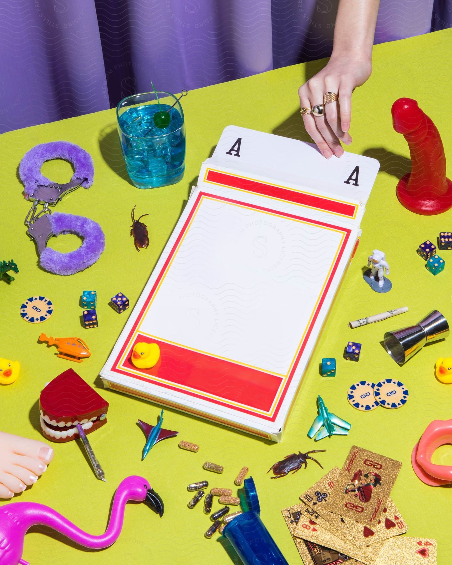 A woman pulls out a large card from a table scattered with sex toys.