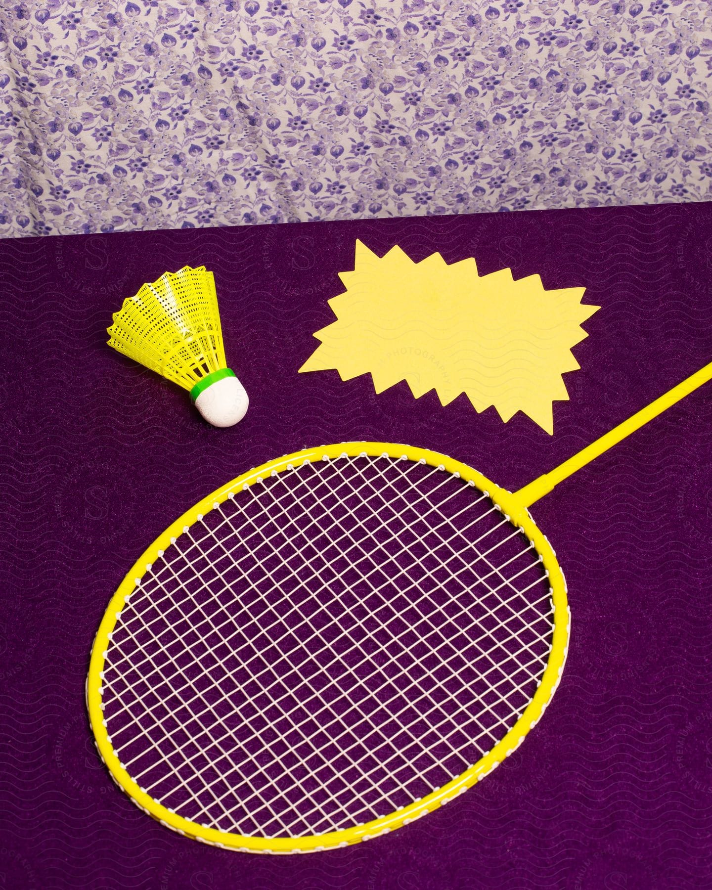 A badminton racket sitting out on a table with a birdie next to it.