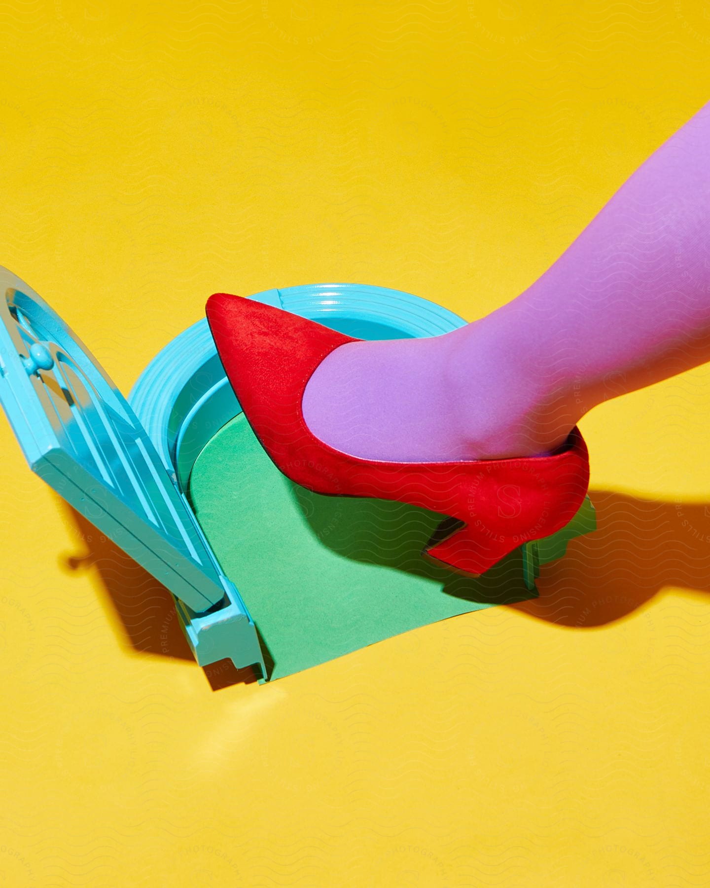 a female feet looking purple and wearing a red shoe as she place her feet on a blue surface in a yellow room