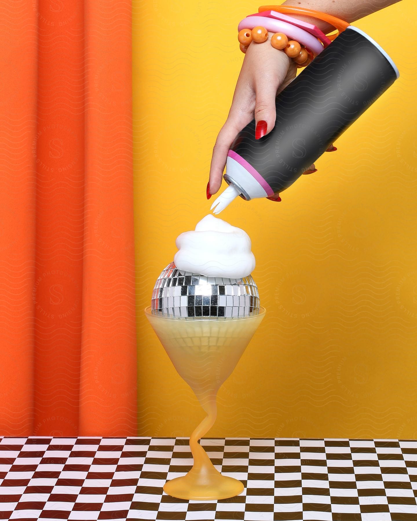 A woman wearing bracelets is topping a disco ball with shaving cream.